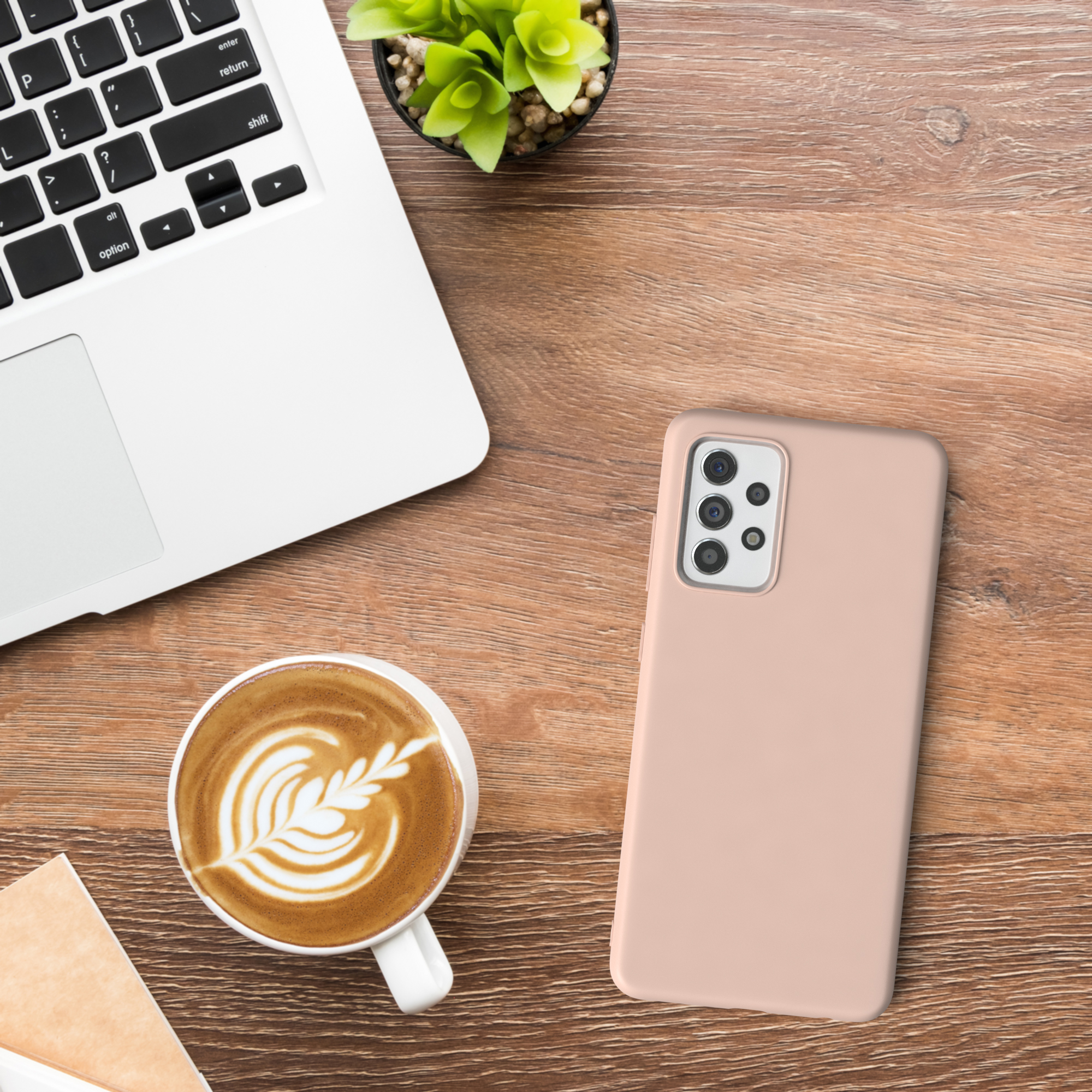 Ein Laptop, ein Telefon, eine Tasse Latte Art und eine Pflanze auf einem Holzschreibtisch.