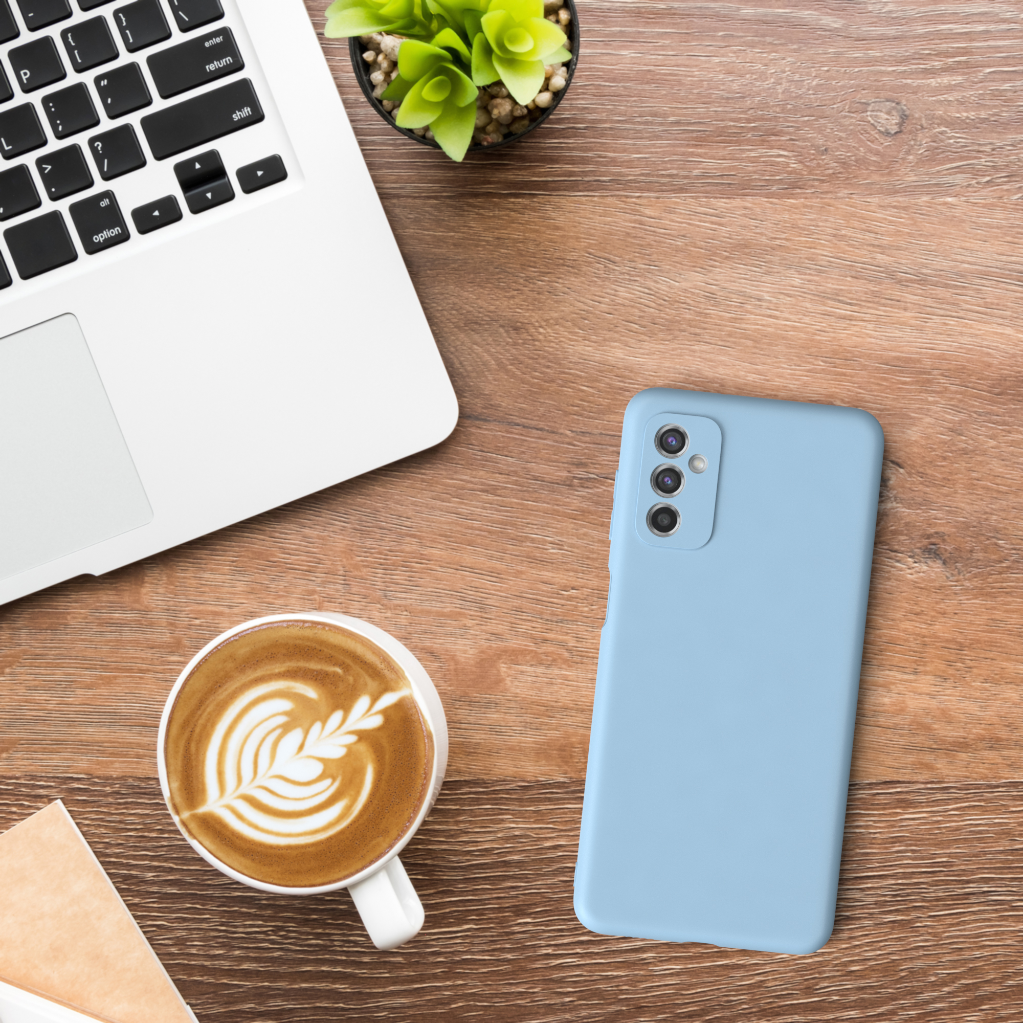 Ein Laptop, ein Telefon, eine Kaffeetasse und eine Pflanze auf einem Holztisch.