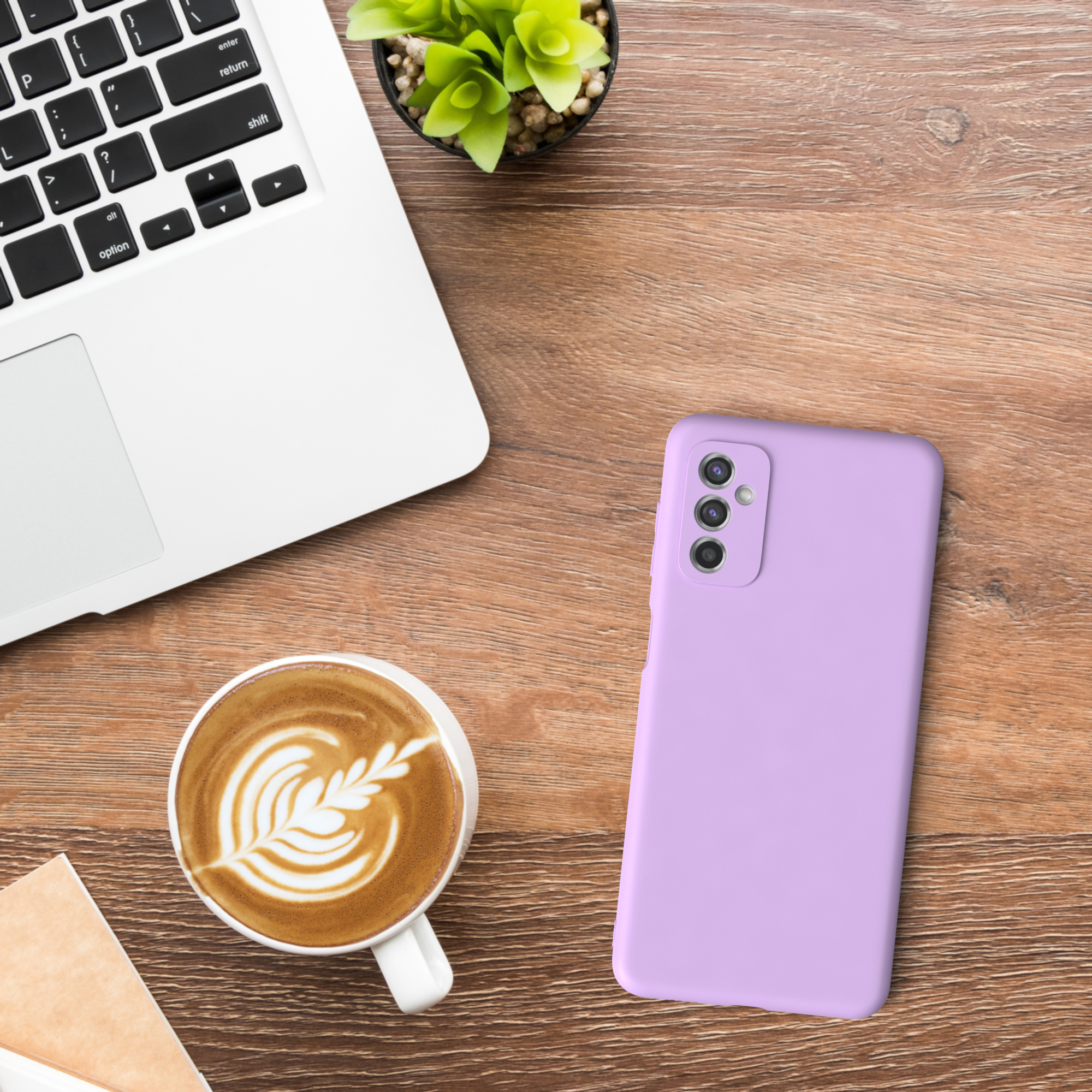 Ein Schreibtisch mit Laptop, Kaffeetasse, Telefon und einer kleinen Pflanze.