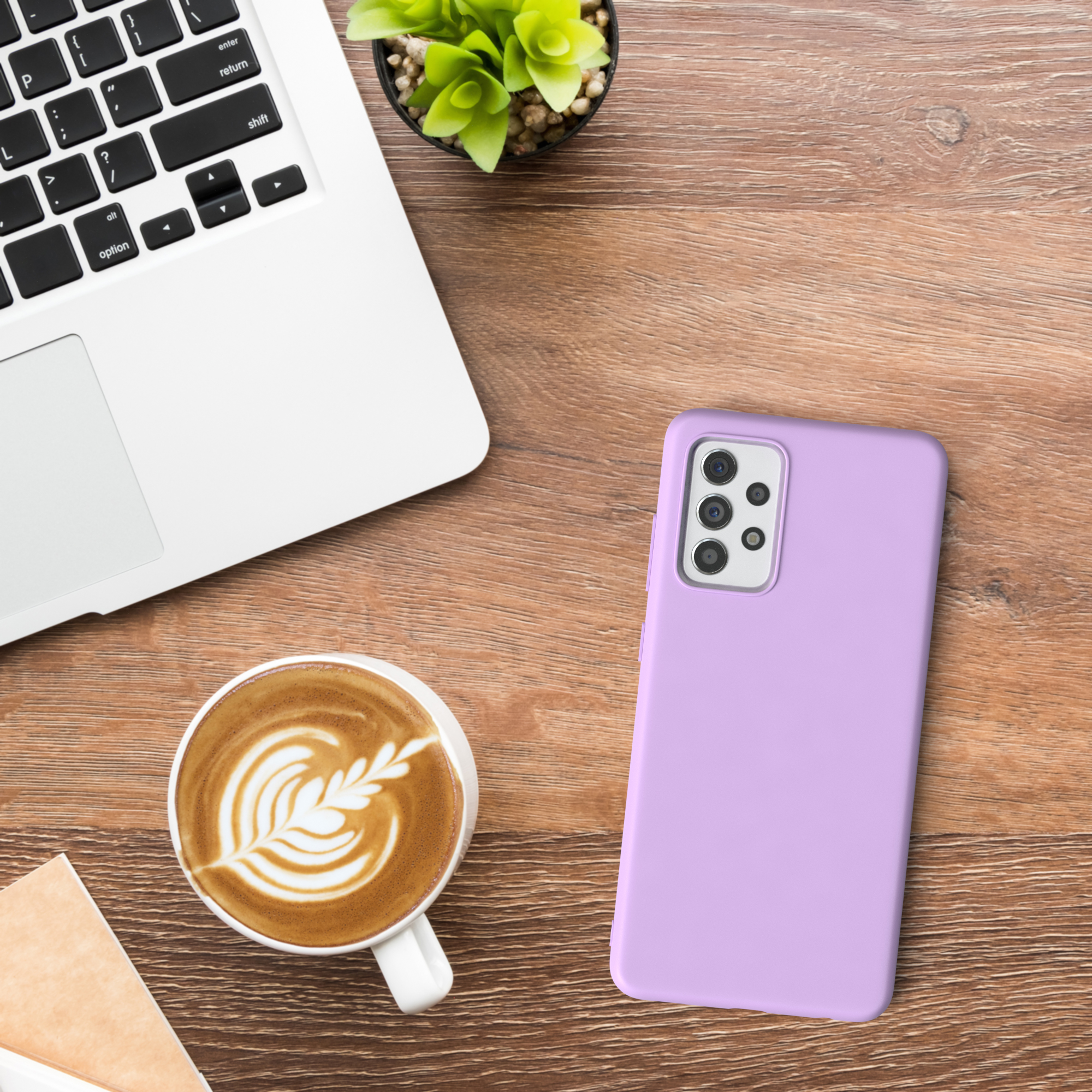 Ein Laptop, eine Kaffeetasse mit Latte Art, ein Telefon und eine Pflanze auf einem Holztisch.