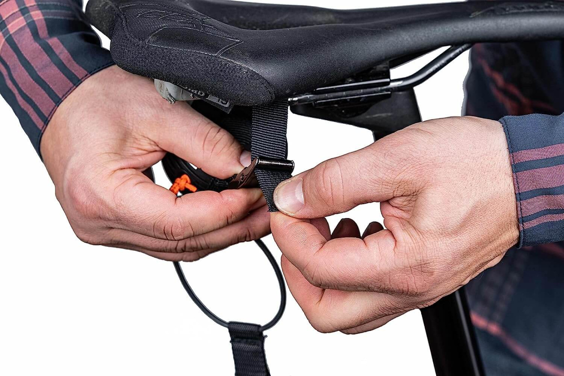 Hände befestigen einen schwarzen Riemen an einem Fahrradsattel, Nahaufnahme.