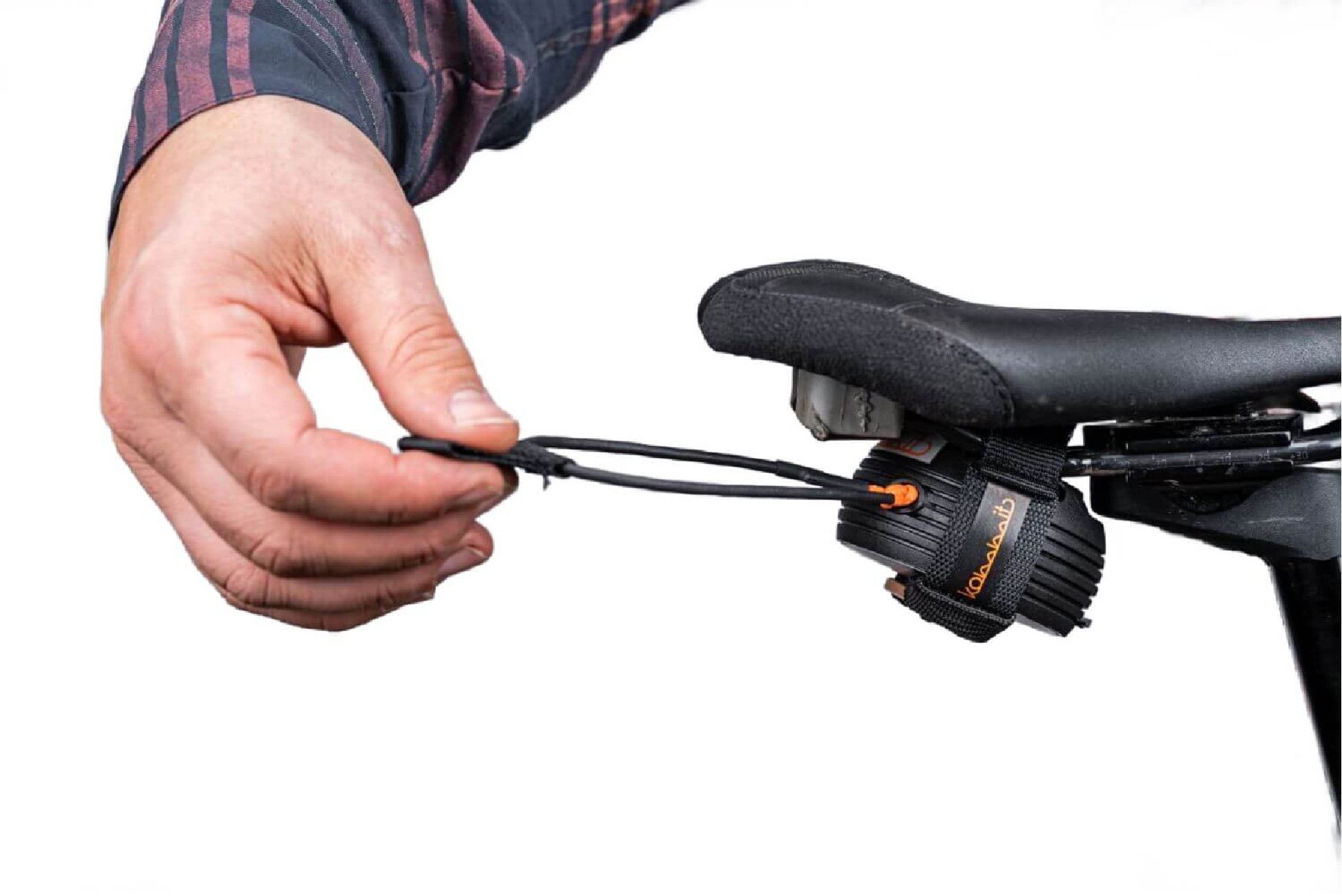 Die Hand einer Person stellt ein Fahrradlicht ein, das an einem Fahrradsitz befestigt ist. Das Licht ist schwarz und orange.