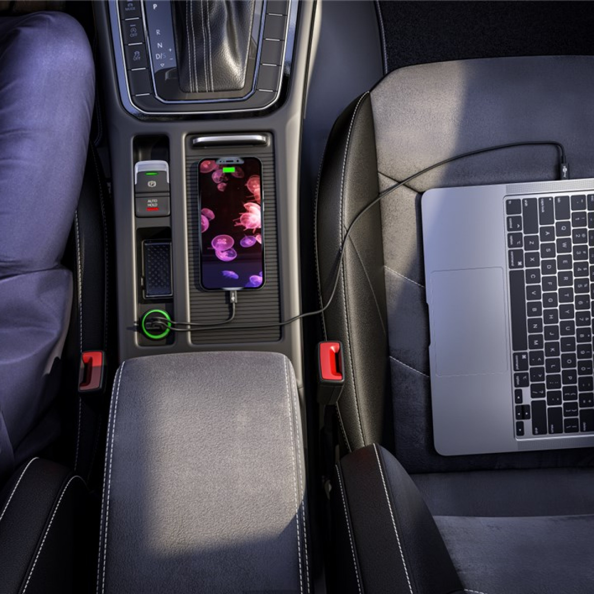 Auto-Innenraum mit Ladung des Telefons. MacBook auf dem Sitz. USB und Autoladegerät.