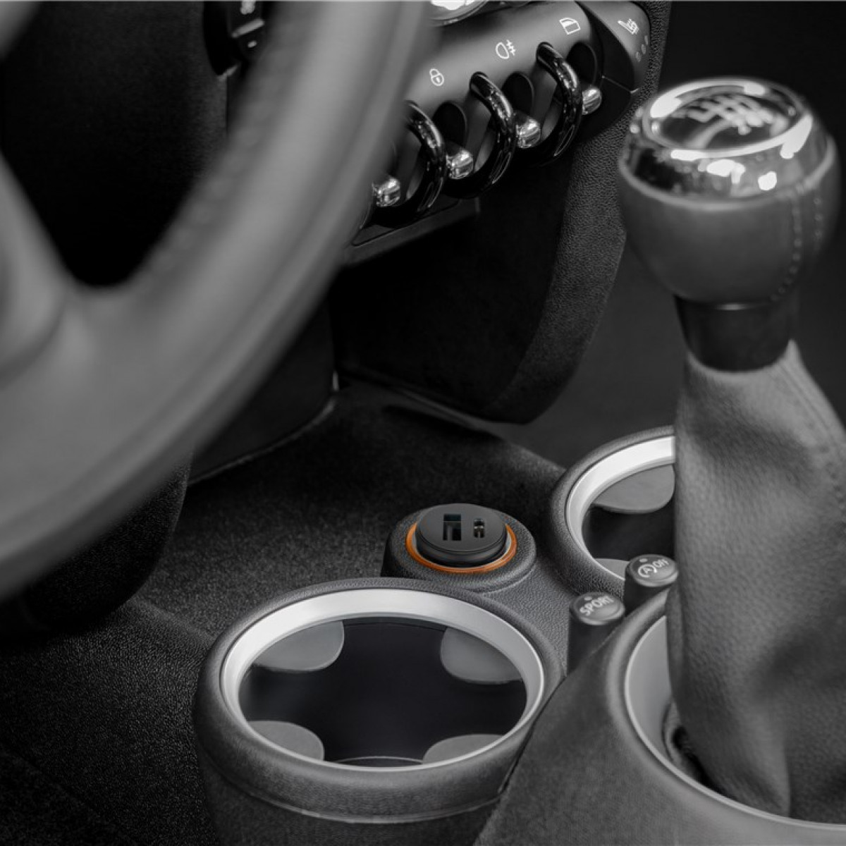 Nahaufnahme des Innenraums eines Autos mit Schalthebel, Getränkehaltern und Armaturenbrett.