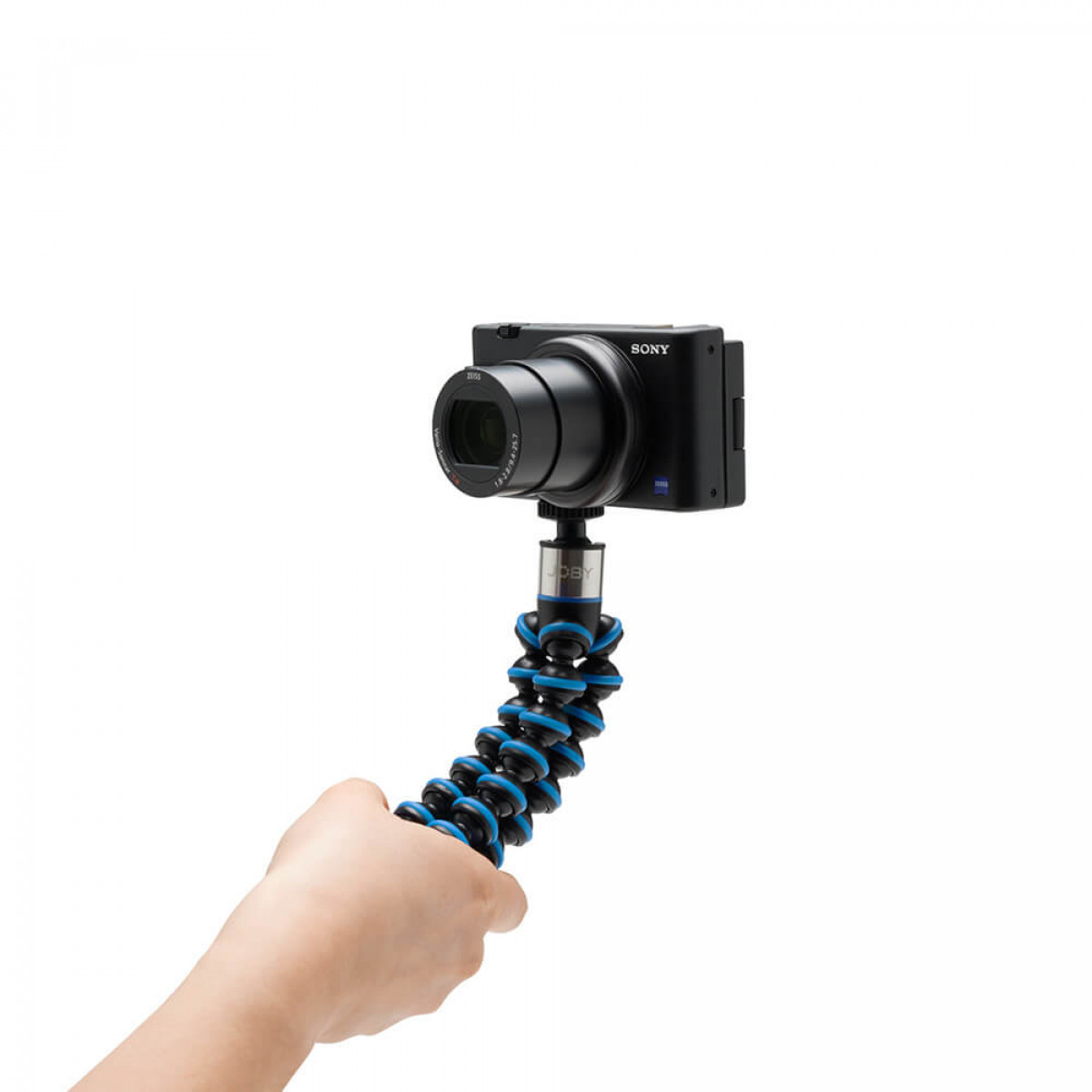 Eine schwarze Kamera, die auf einem flexiblen blauen und schwarzen Stativ montiert ist, das von einer Hand gehalten wird.