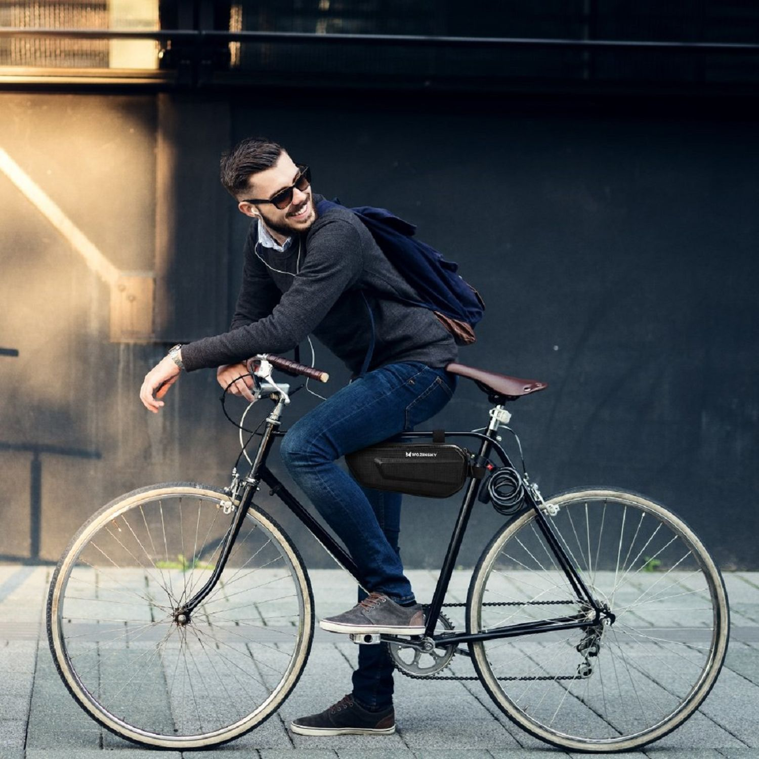 Mann auf einem Fahrrad, der auf einer Straße in der Stadt fährt, trägt Sonnenbrille und Rucksack.
