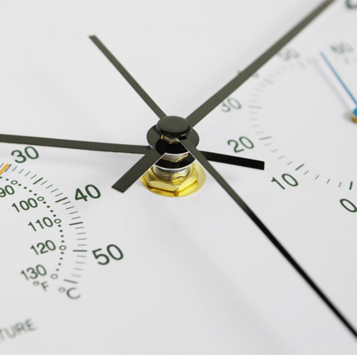 Zbliżenie białej tarczy zegara z czarnymi wskazówkami i wskaźnikami temperatury.