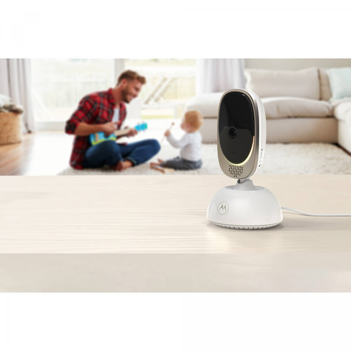 Babyphone auf einem Tisch mit einer Familie im unscharfen Hintergrund. Ein Mann und ein Baby sind sichtbar.