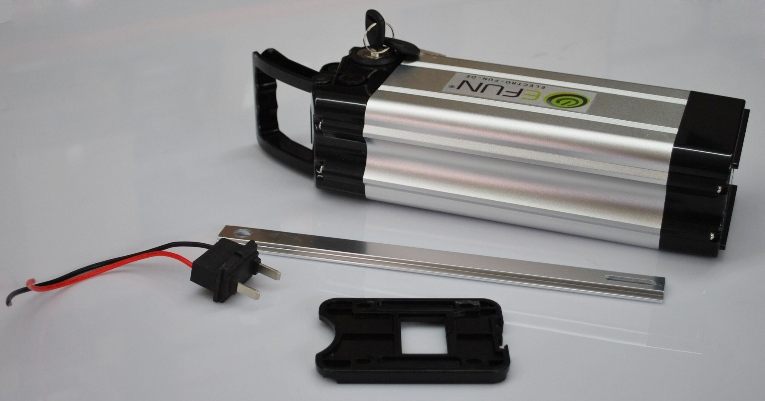 Silber-schwarzer E-Bike-Akku mit Stecker und Metallstreifen auf weißer Oberfläche.