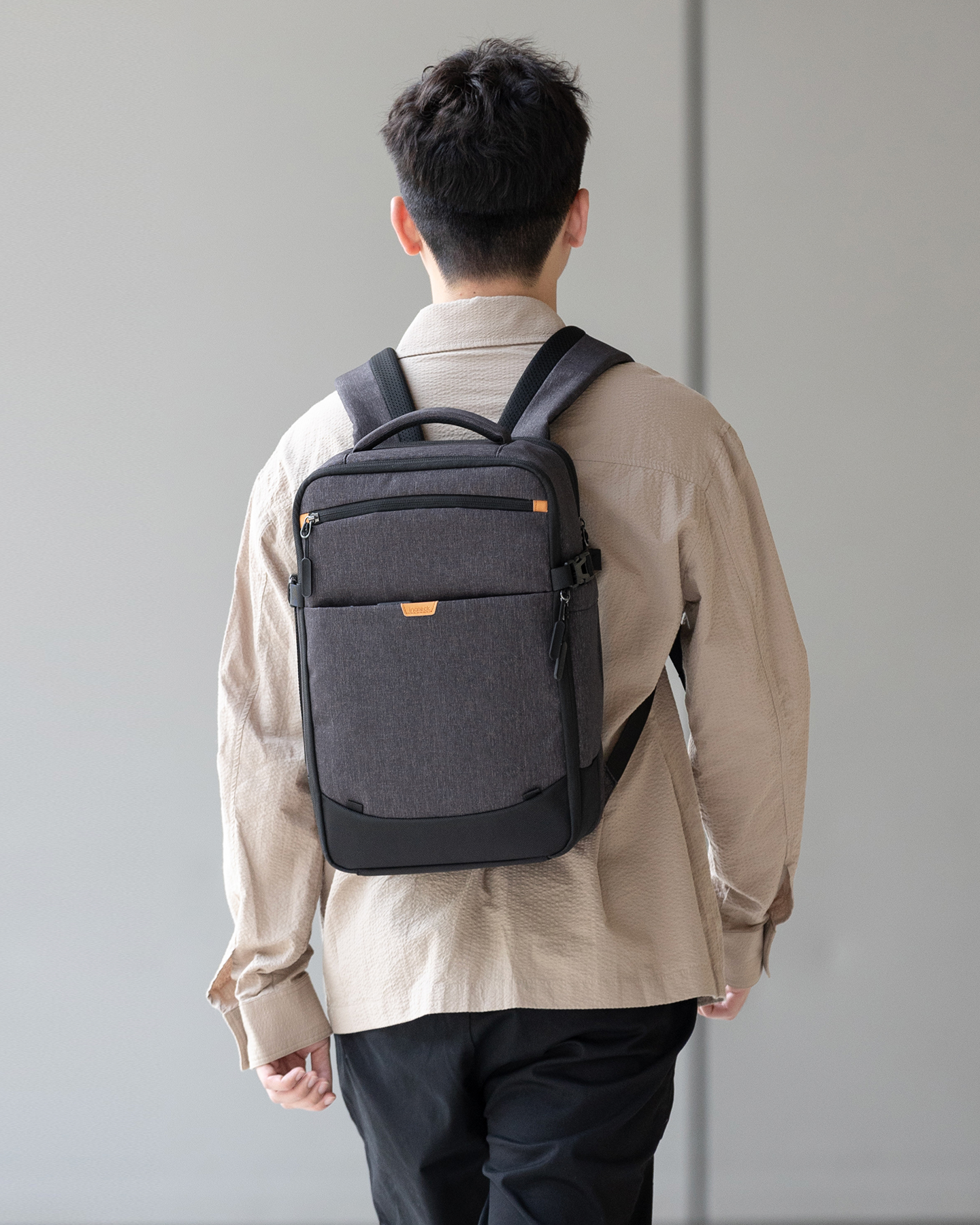Mann von hinten mit Rucksack. Das Gebäude befindet sich im Hintergrund.