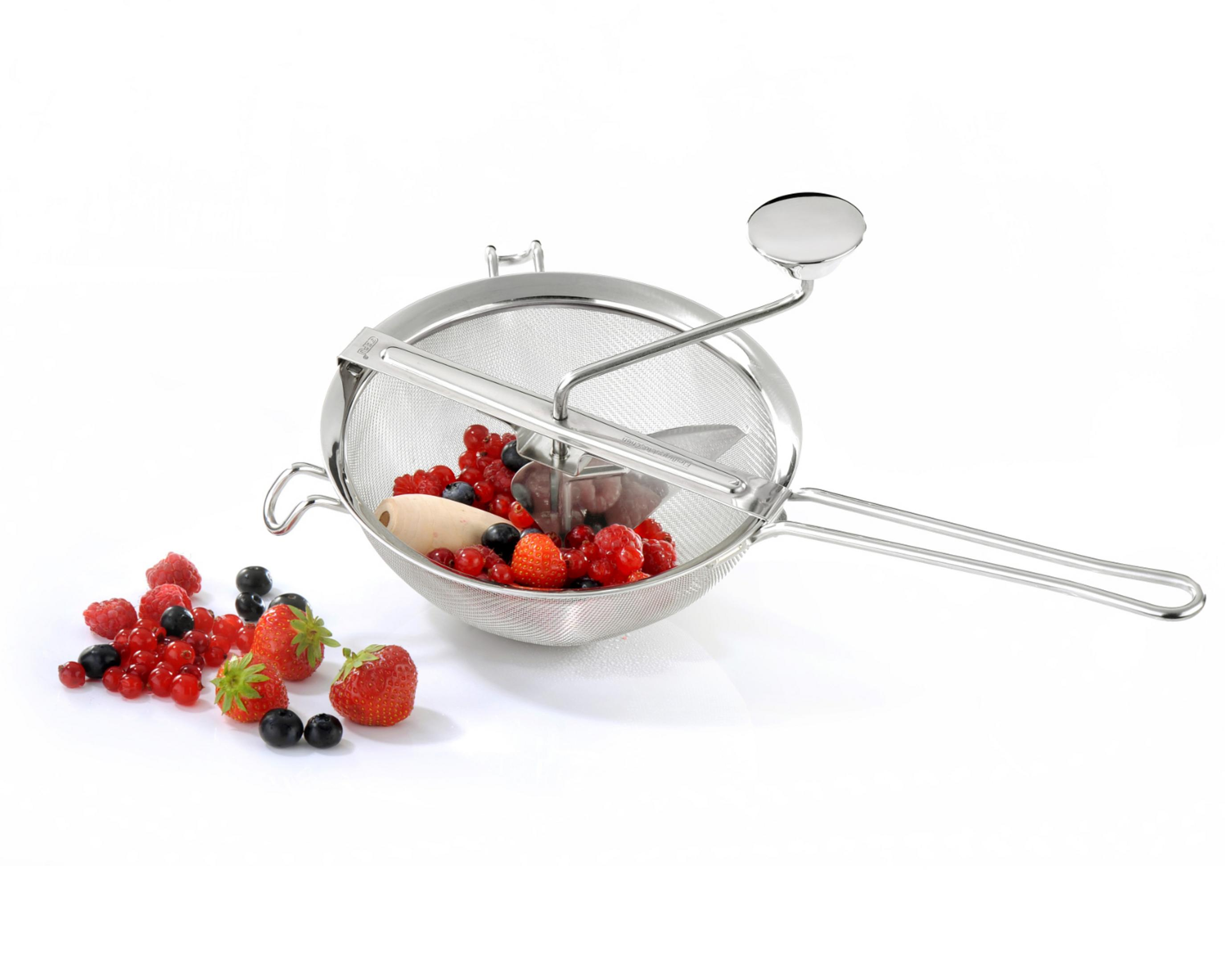 Eine Küchenmühle mit Beeren. Edelstahl, Beeren darin. Weißer Hintergrund.