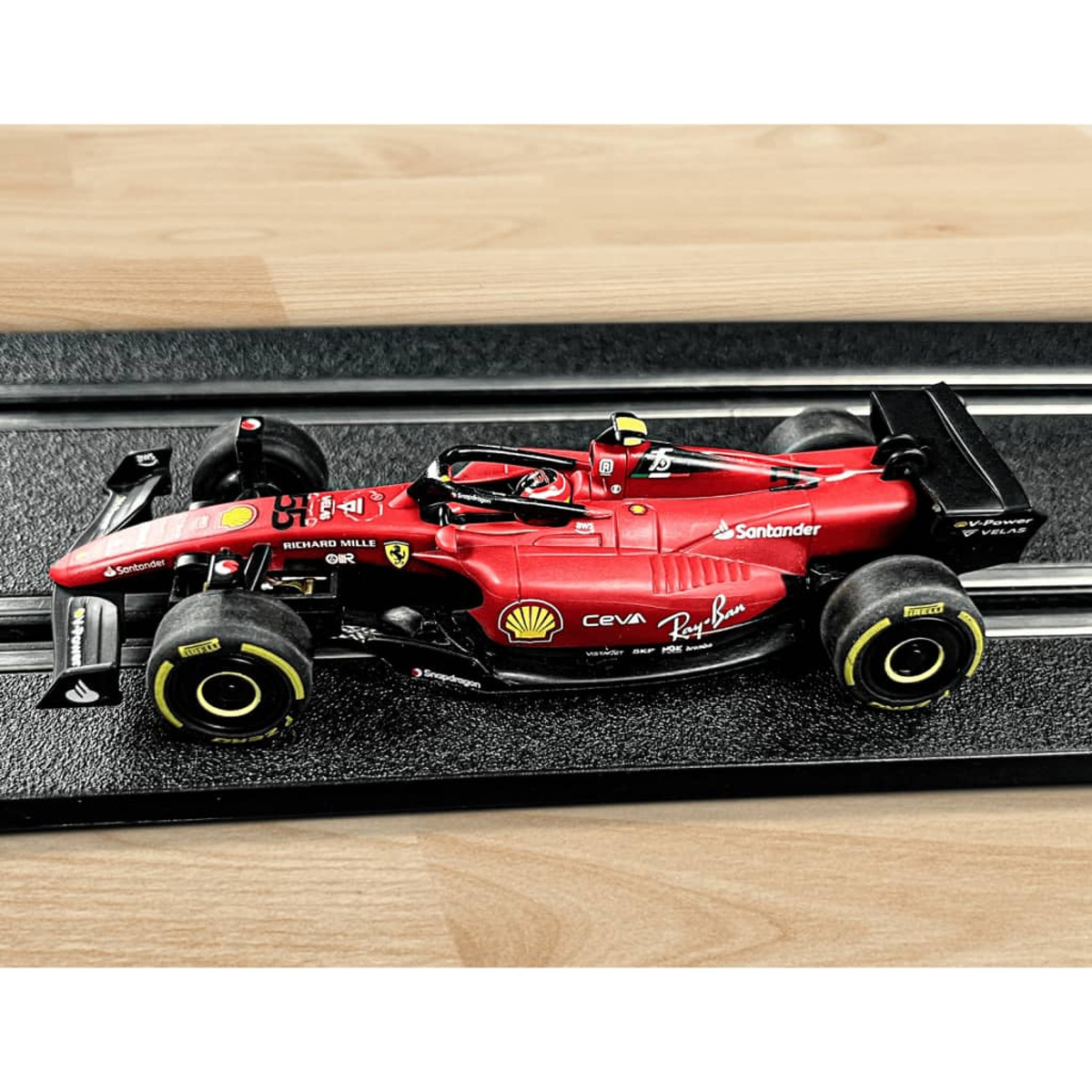 Czerwony model samochodu wyścigowego Ferrari na czarnym torze. Samochód ma loga sponsorów.