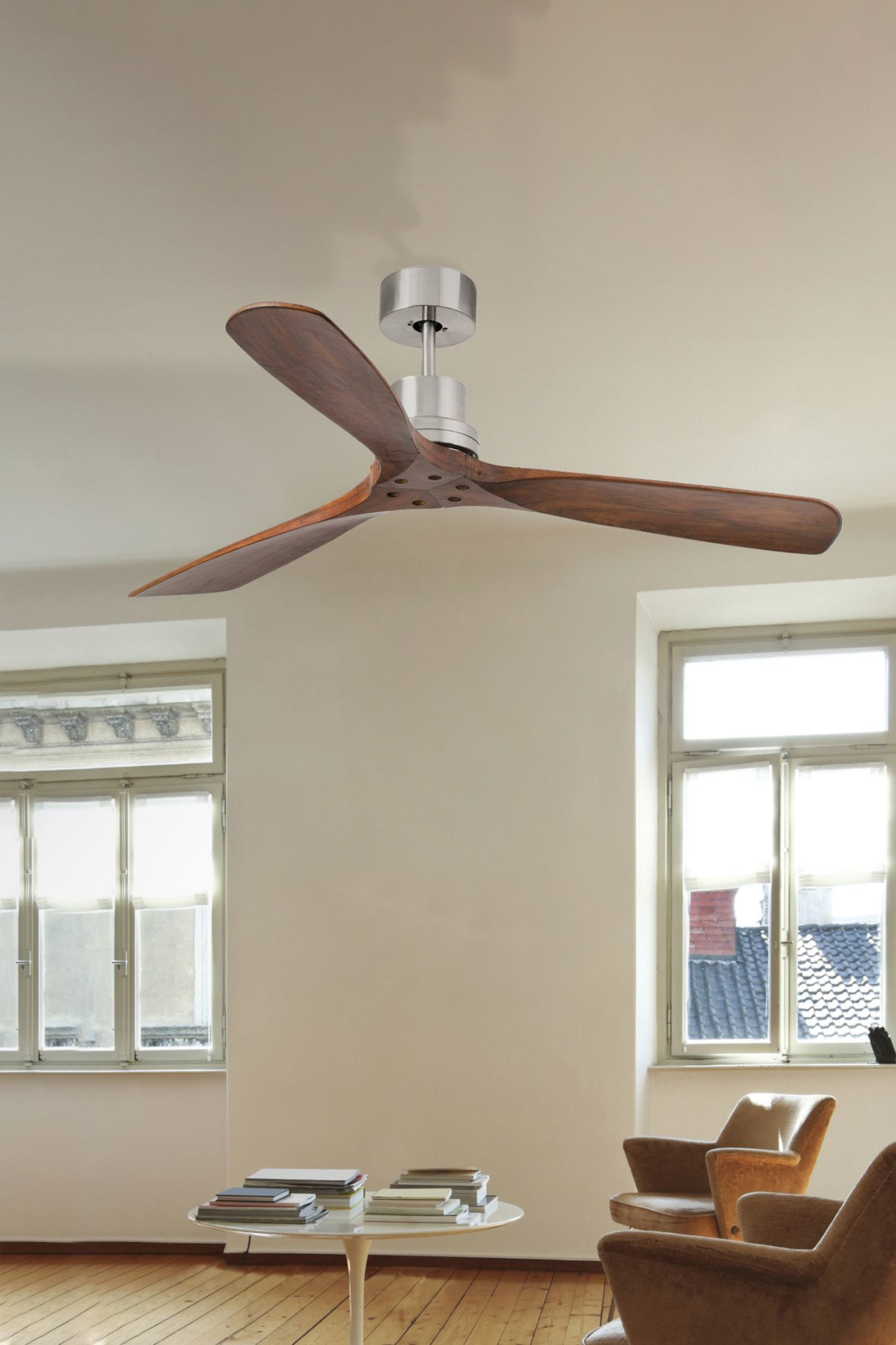 Deckenventilator aus Holz mit drei Flügeln. In einem weißen Raum mit zwei Fenstern.