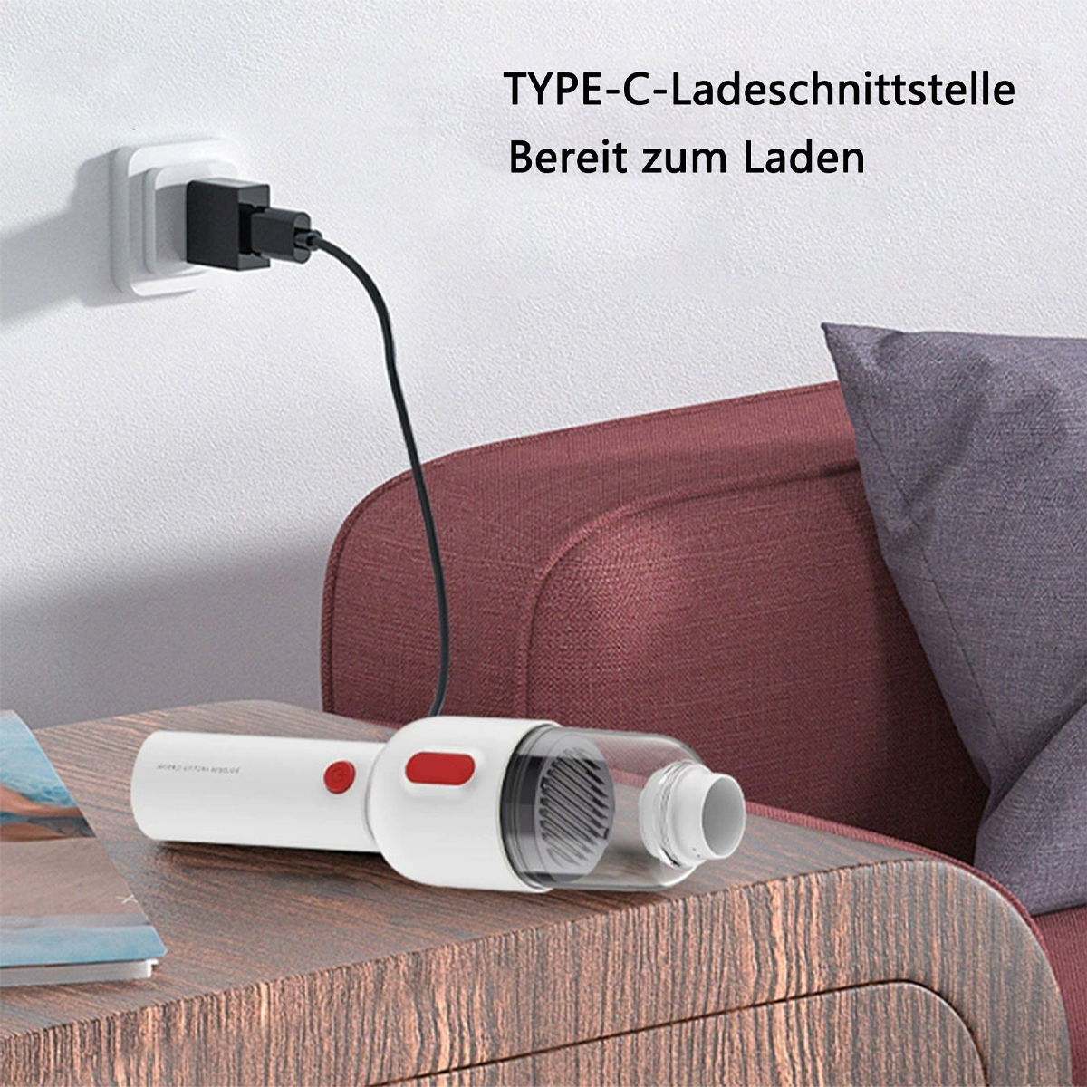 Biały odkurzacz z czerwonym przyciskiem, ładujący się przez gniazdko ścienne. Na stole.