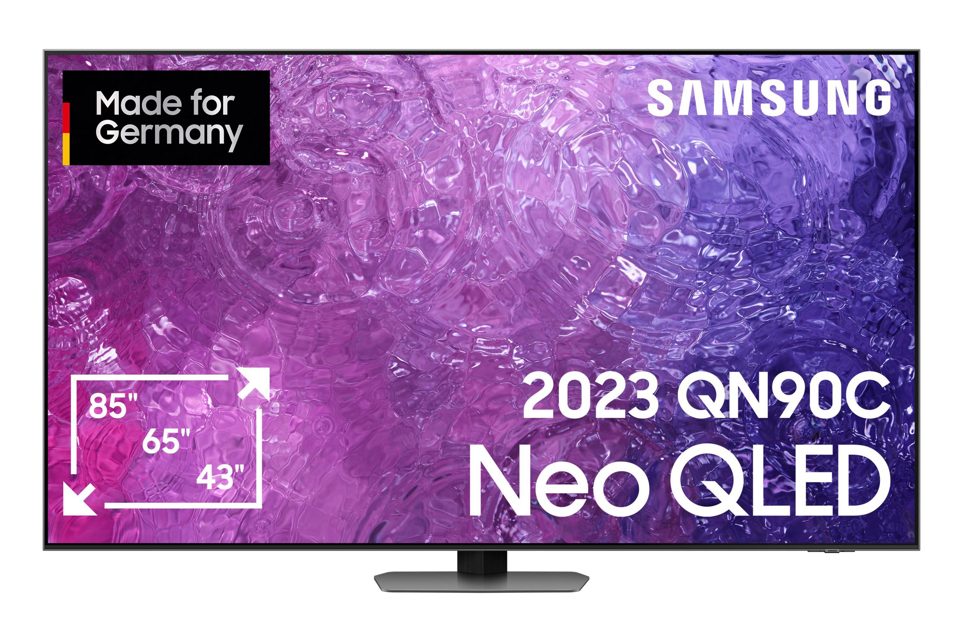 Ein großer Samsung Neo QLED-Fernseher mit schwarzem Rahmen, der farbenfrohe Bilder anzeigt und den Text 2023 QN90C.