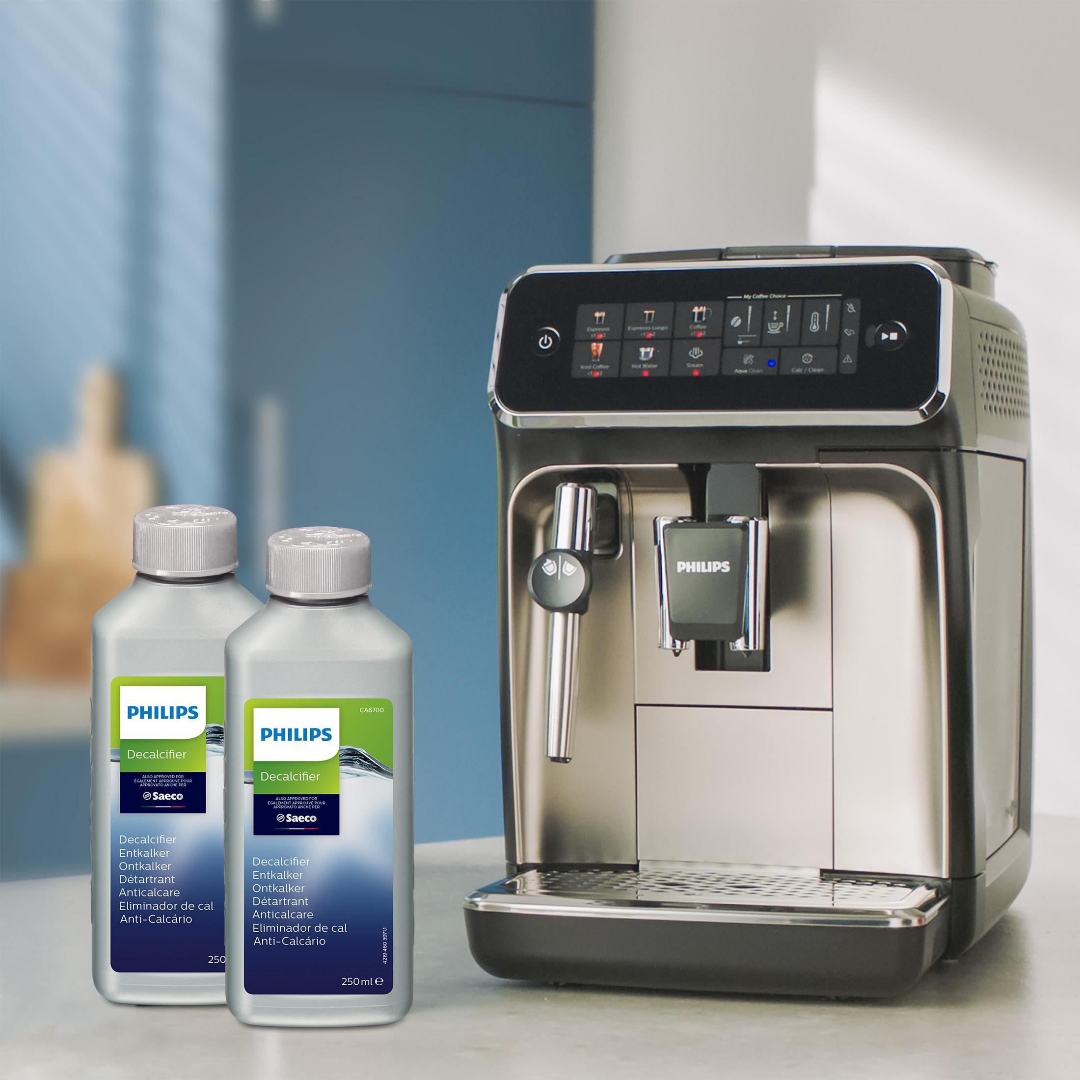 Kaffeemaschine und zwei Flaschen Entkalker auf einer Theke. Der Hintergrund hat eine blaue Wand. Die Maschine ist schwarz.
