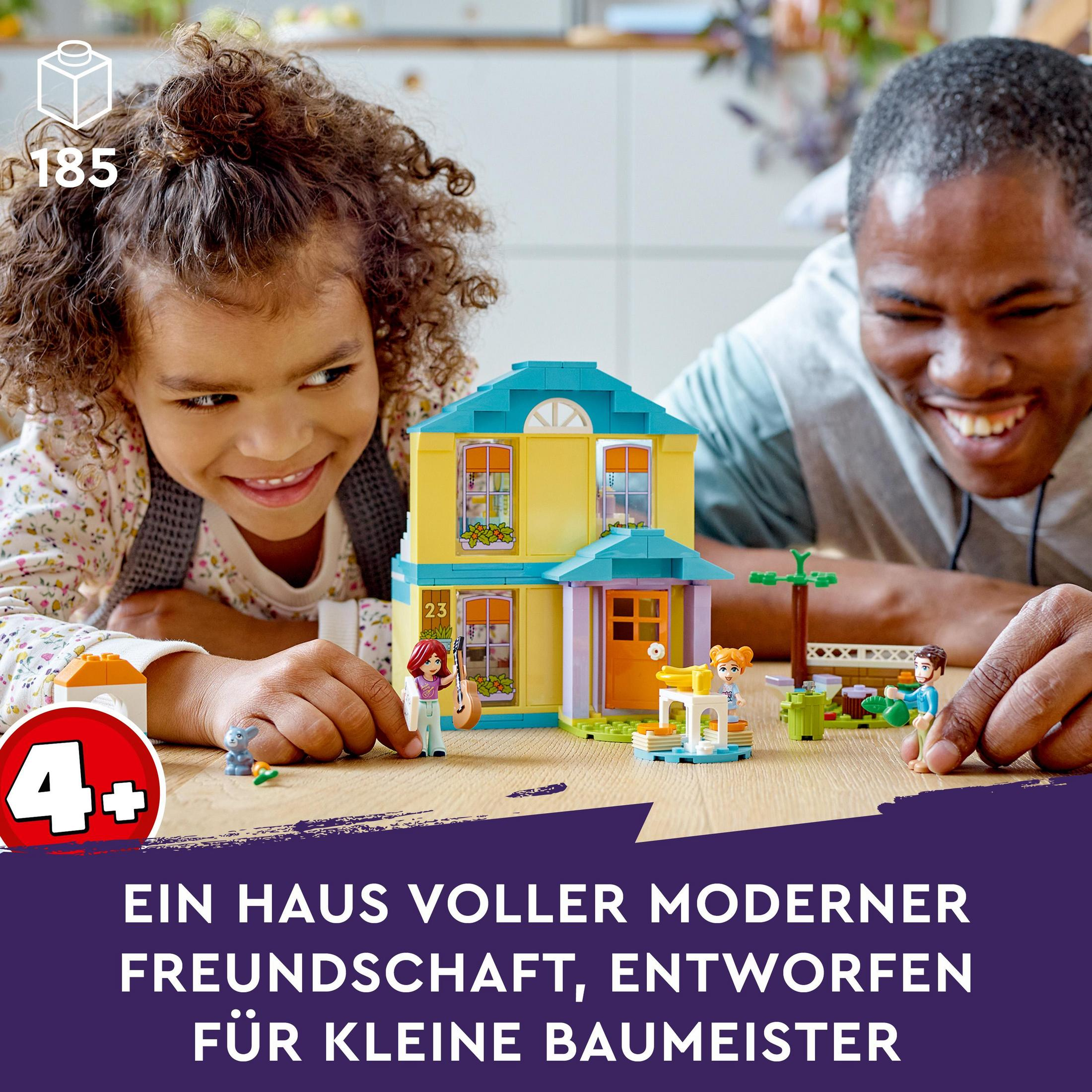 Ein Mädchen und ein Mann spielen mit einem Lego-Haus. Das Haus ist gelb und blau.