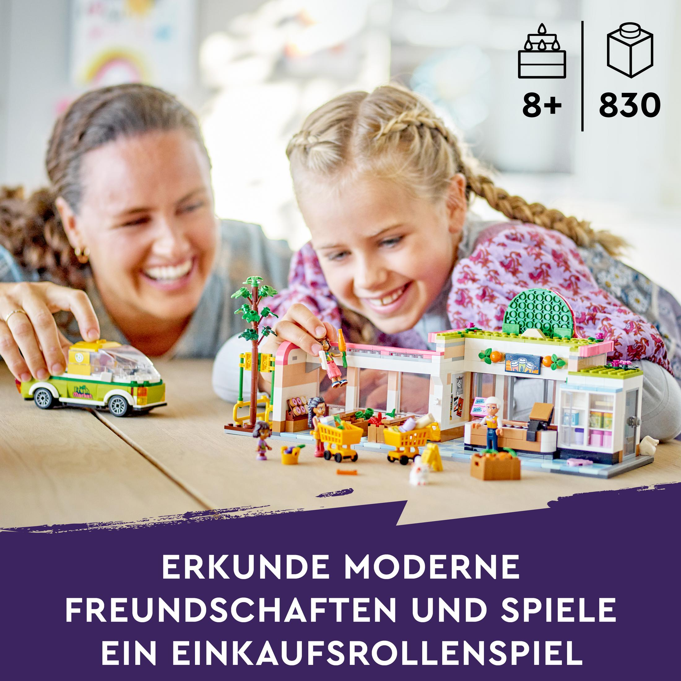 Mutter und Tochter bauen ein Lego-Set mit einem Geschäft. Text: Entdecke moderne Freundschaften und spiele.