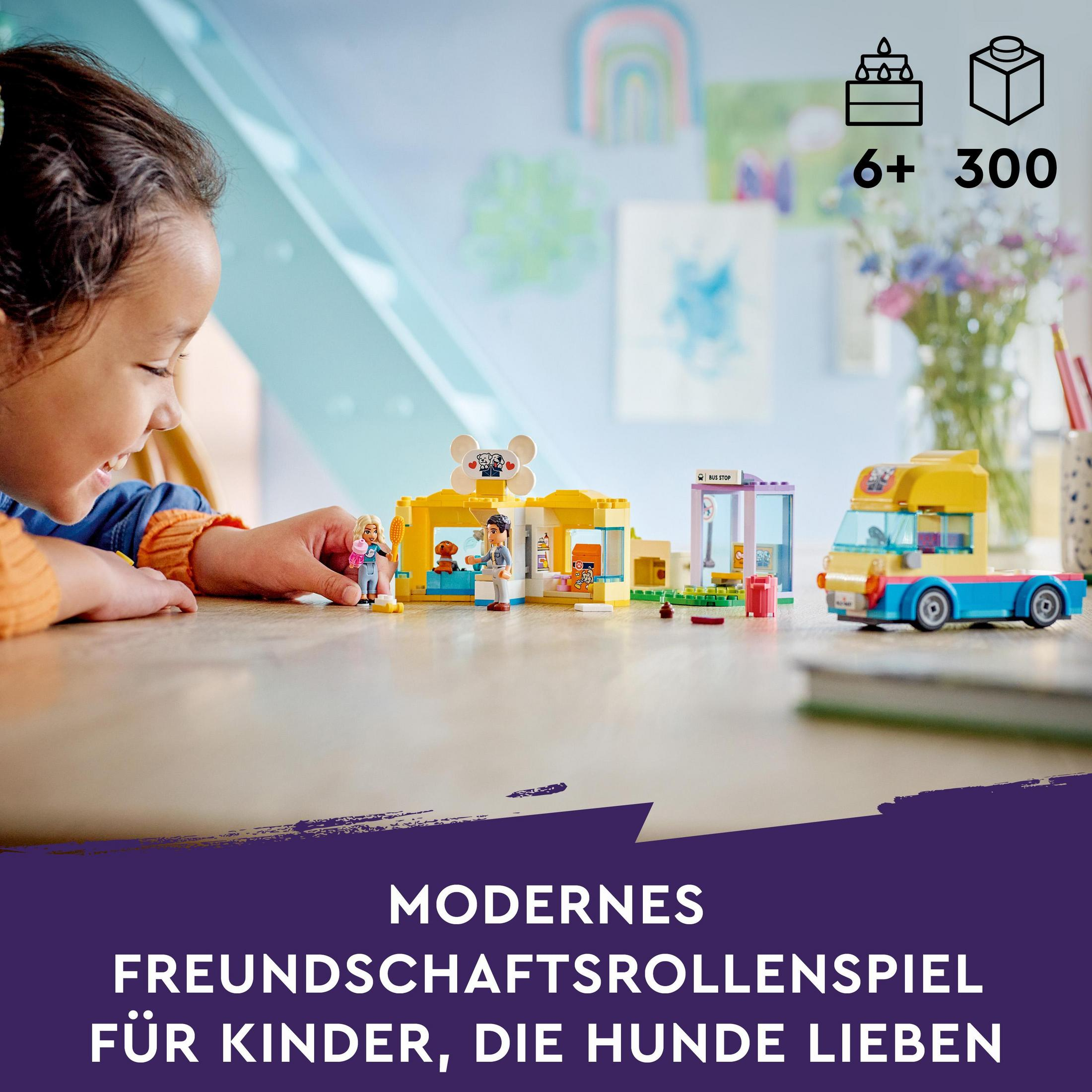 Un bambino che gioca con un set Lego. Il set include edifici a tema cani e un camion.