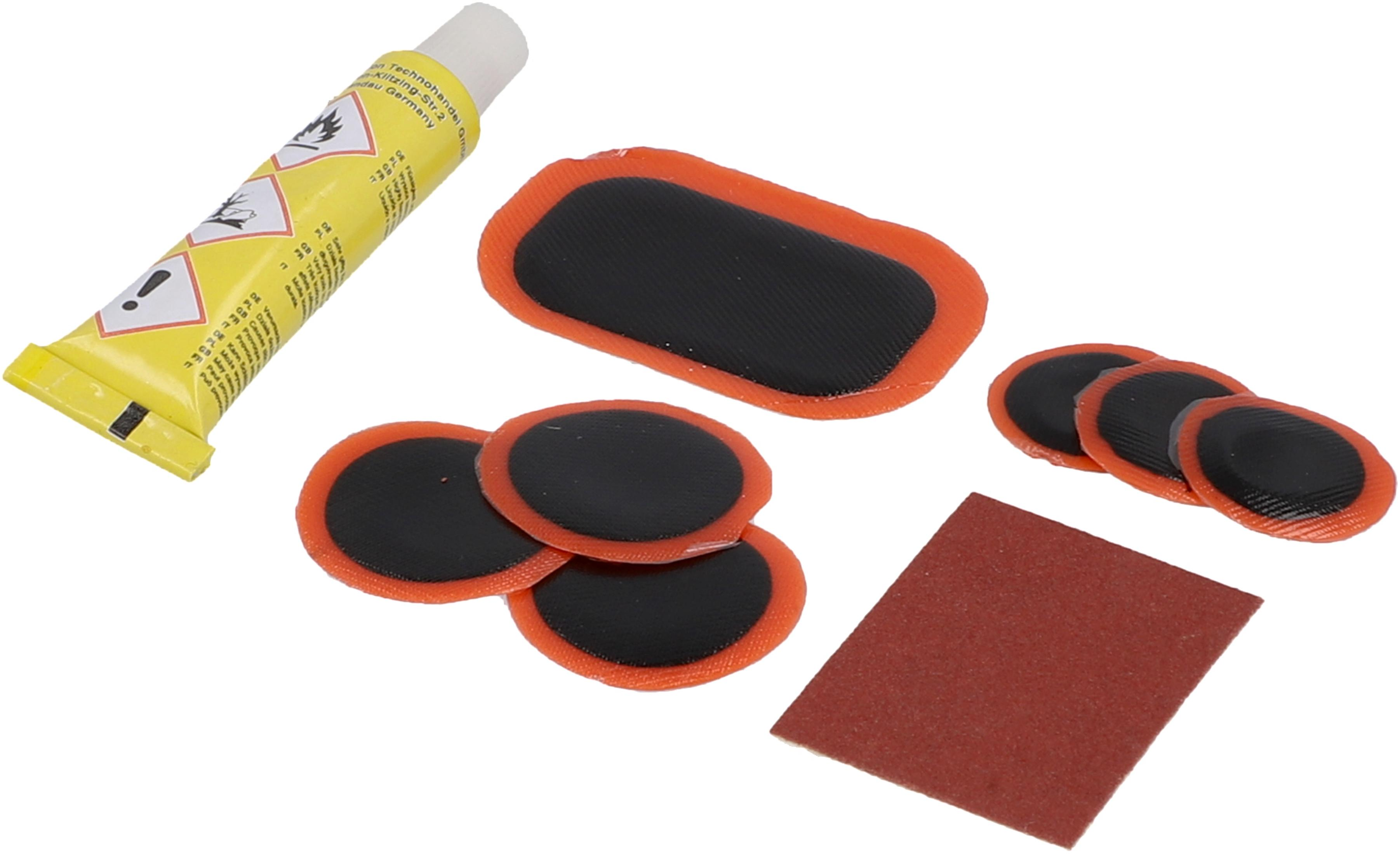 Reifenreparatur-Set mit Kleber, Flicken, Schleifpapier und Flicken auf weißem Hintergrund.
