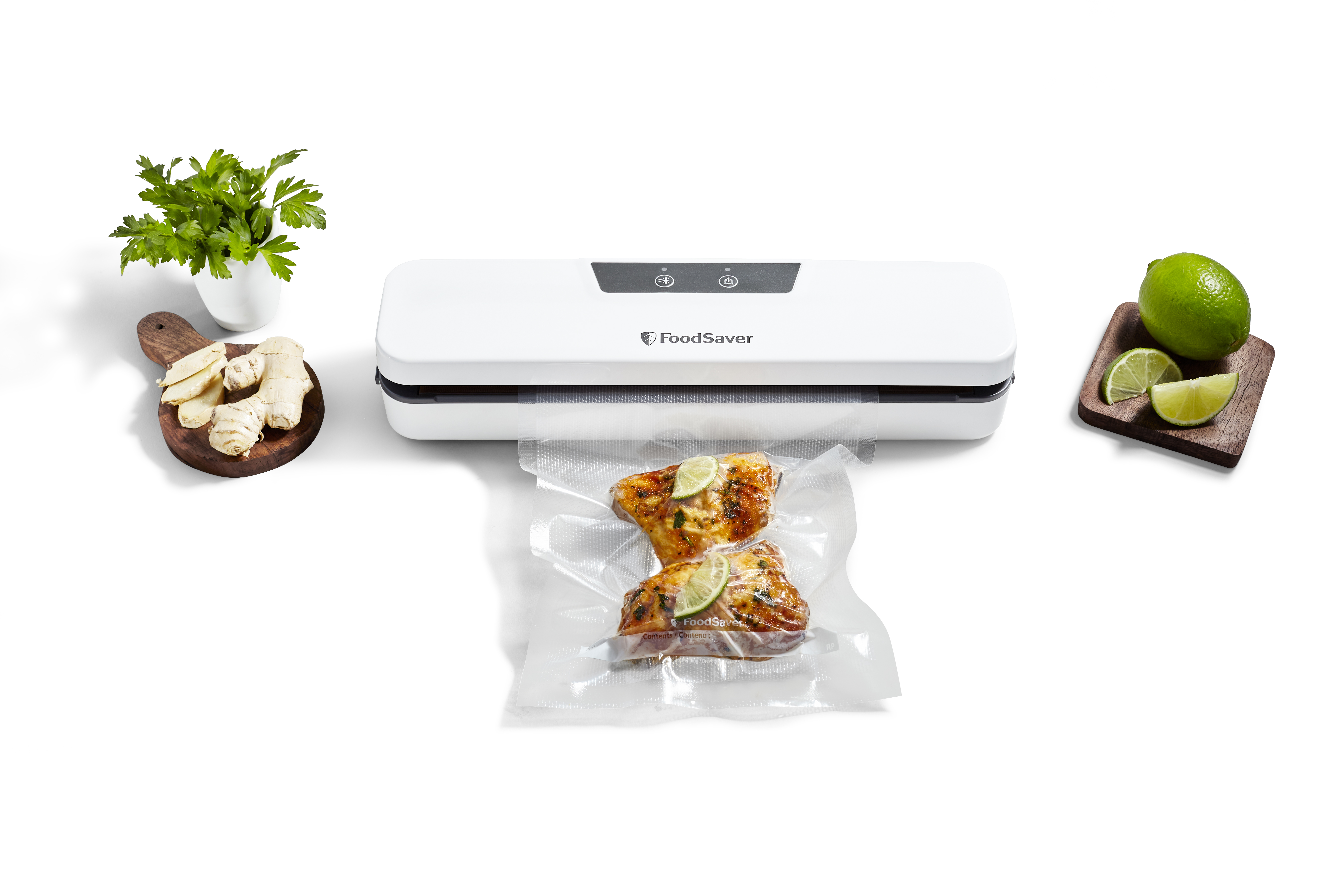 Zgrzewarka próżniowa FoodSaver z jedzeniem w zamkniętej torbie, plasterkami limonki, imbirem i pietruszką.