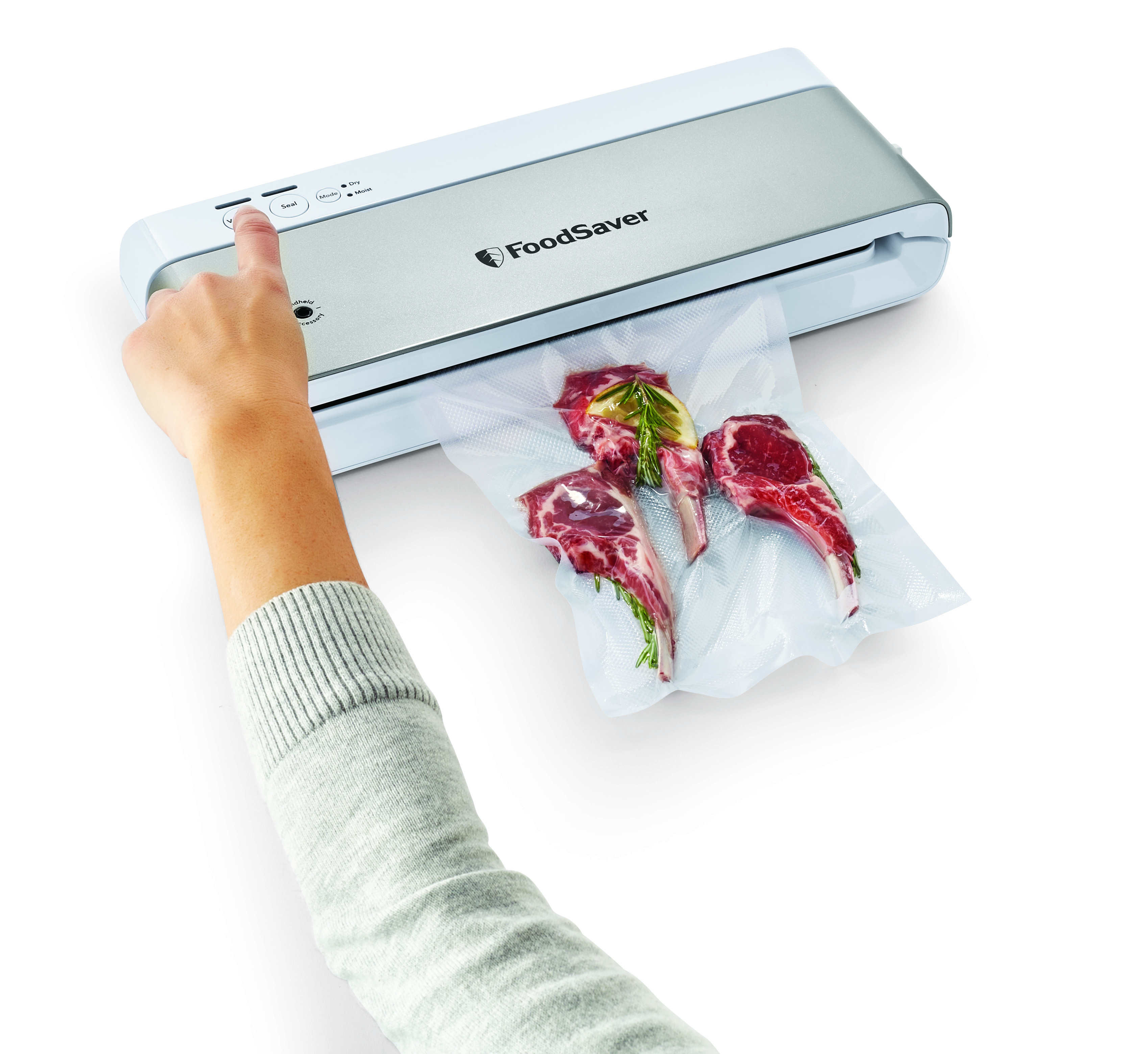 Zgrzewarka próżniowa FoodSaver z ręką naciskającą przycisk uszczelniania i trochę mięsa.