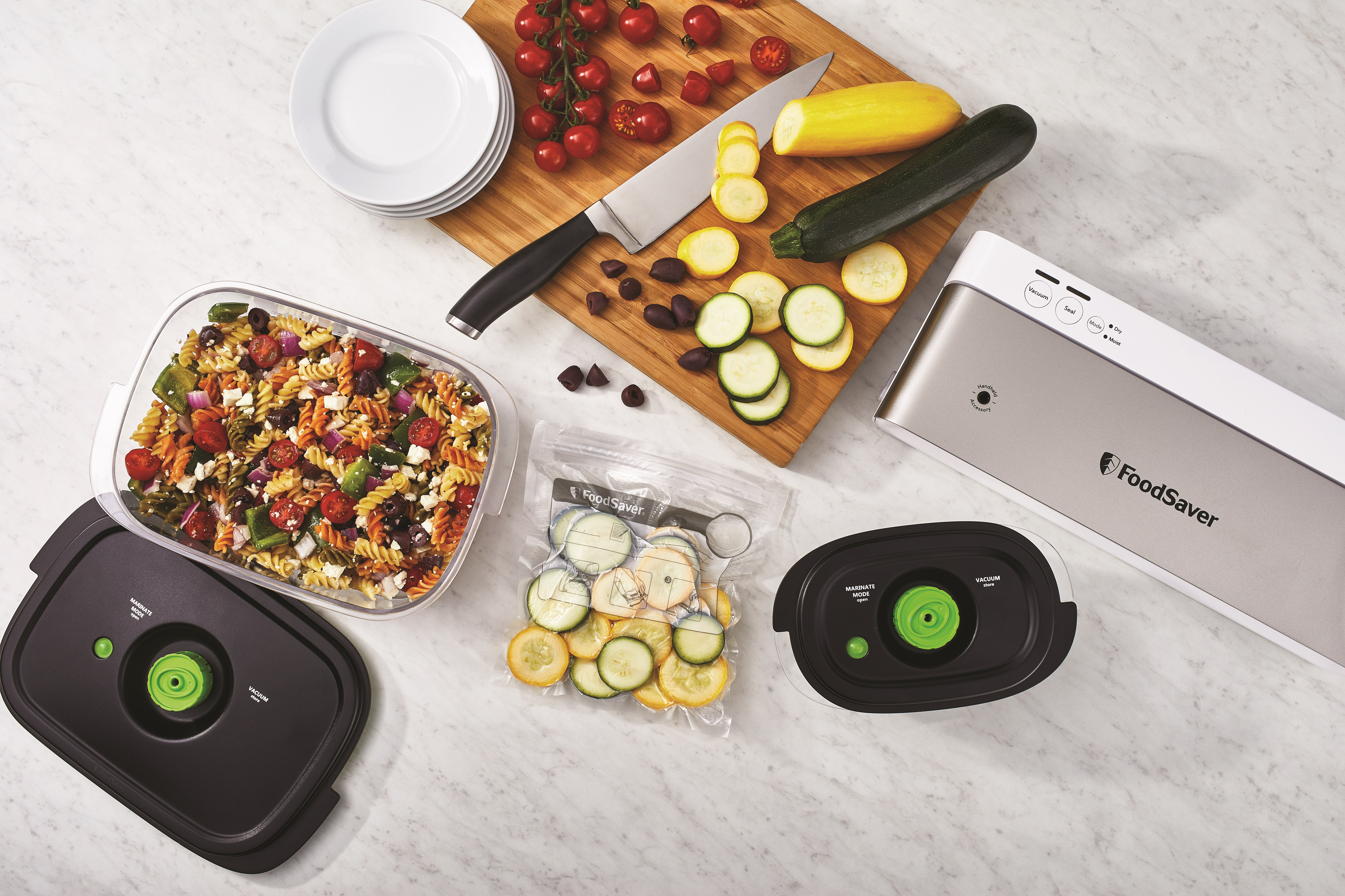 Widok z góry na przygotowywanie jedzenia: makaron, warzywa, nóż, deska do krojenia, zgrzewarka.