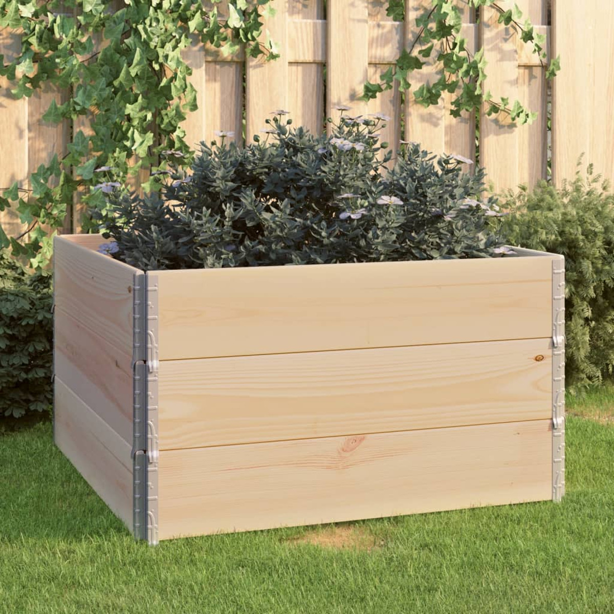 Holzpflanzkasten mit Pflanzen auf einer Rasenfläche, mit Holzzaun im Hintergrund.