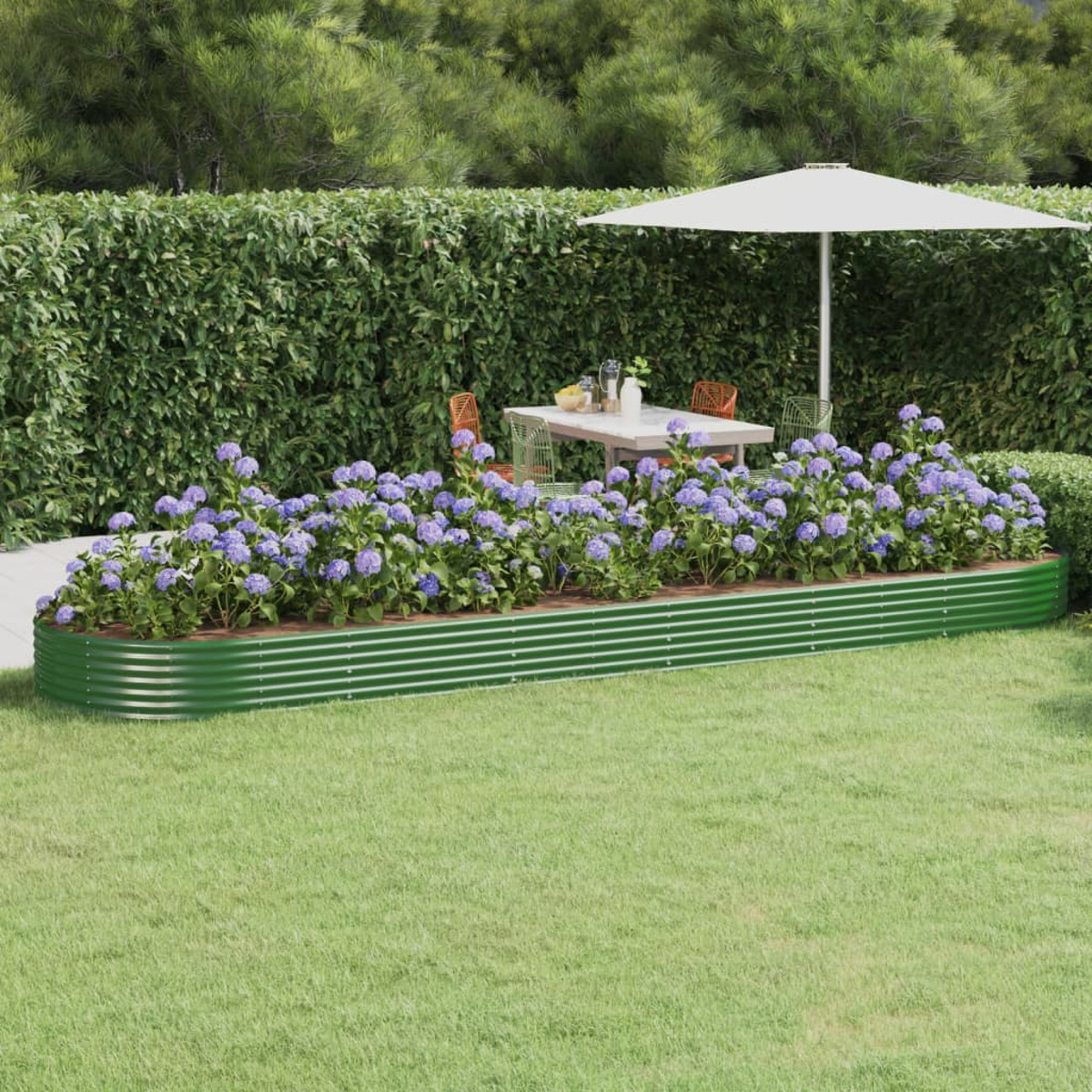 Erhöhtes grünes Gartenbeet mit blauen Blumen, Tisch und Sonnenschirm im Garten.