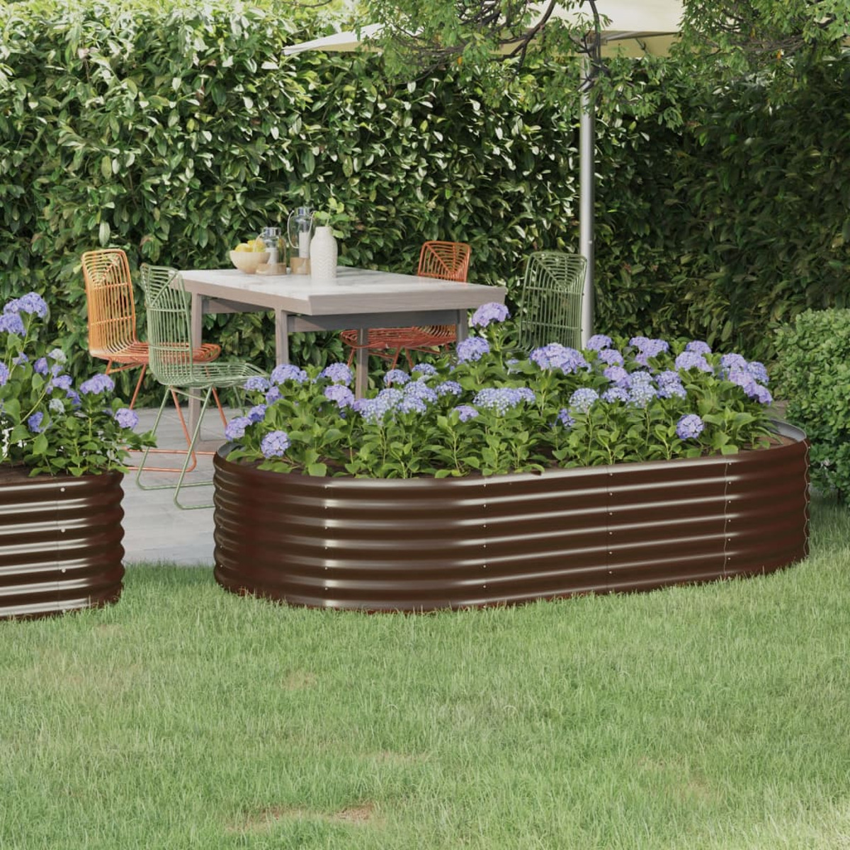 Ein Garten mit Pflanzen in braunen Metallpflanzgefäßen. Ein Tisch und Stühle sind sichtbar.