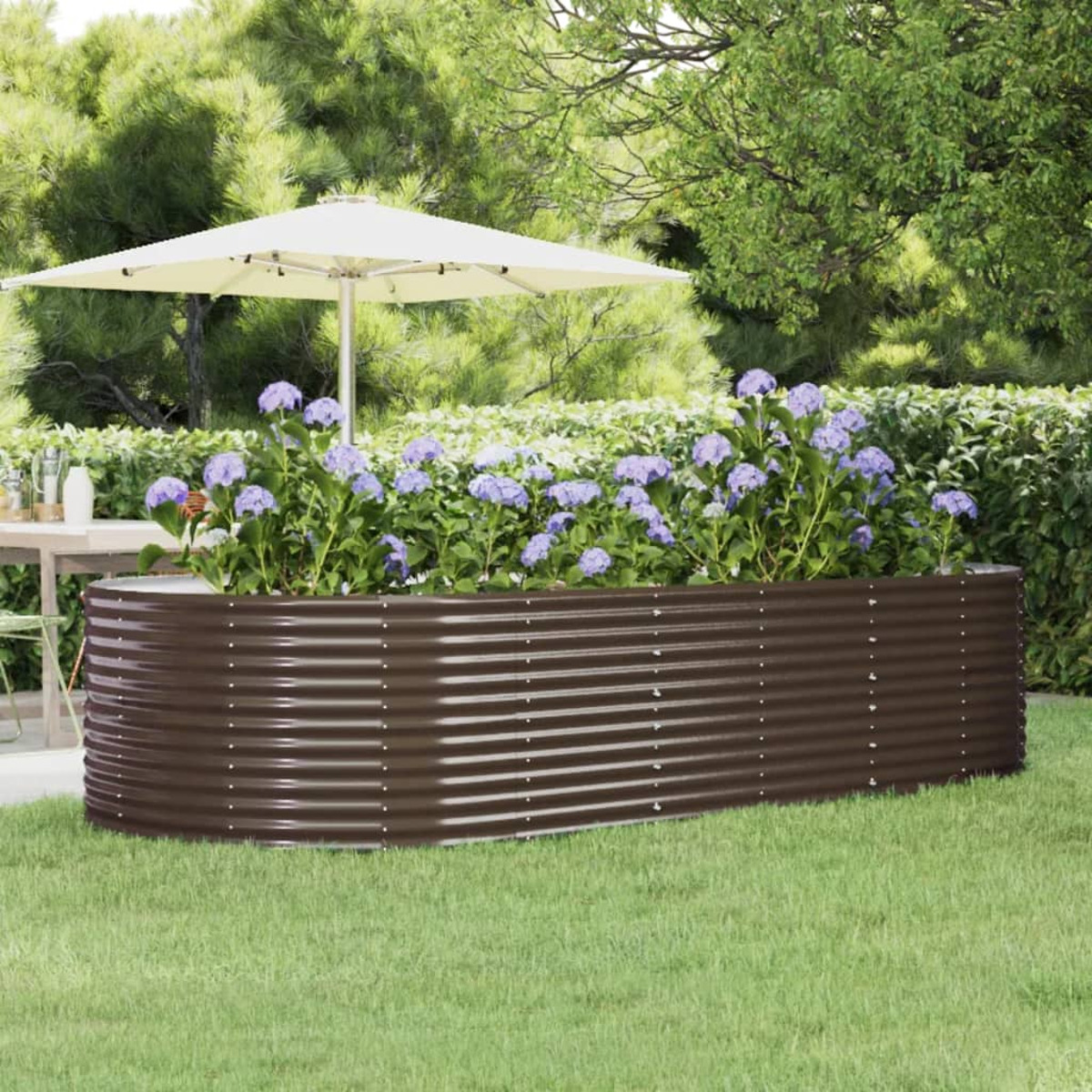 Ein langer, brauner Metallpflanzer in einem Garten. Blumen sind im Pflanzer.