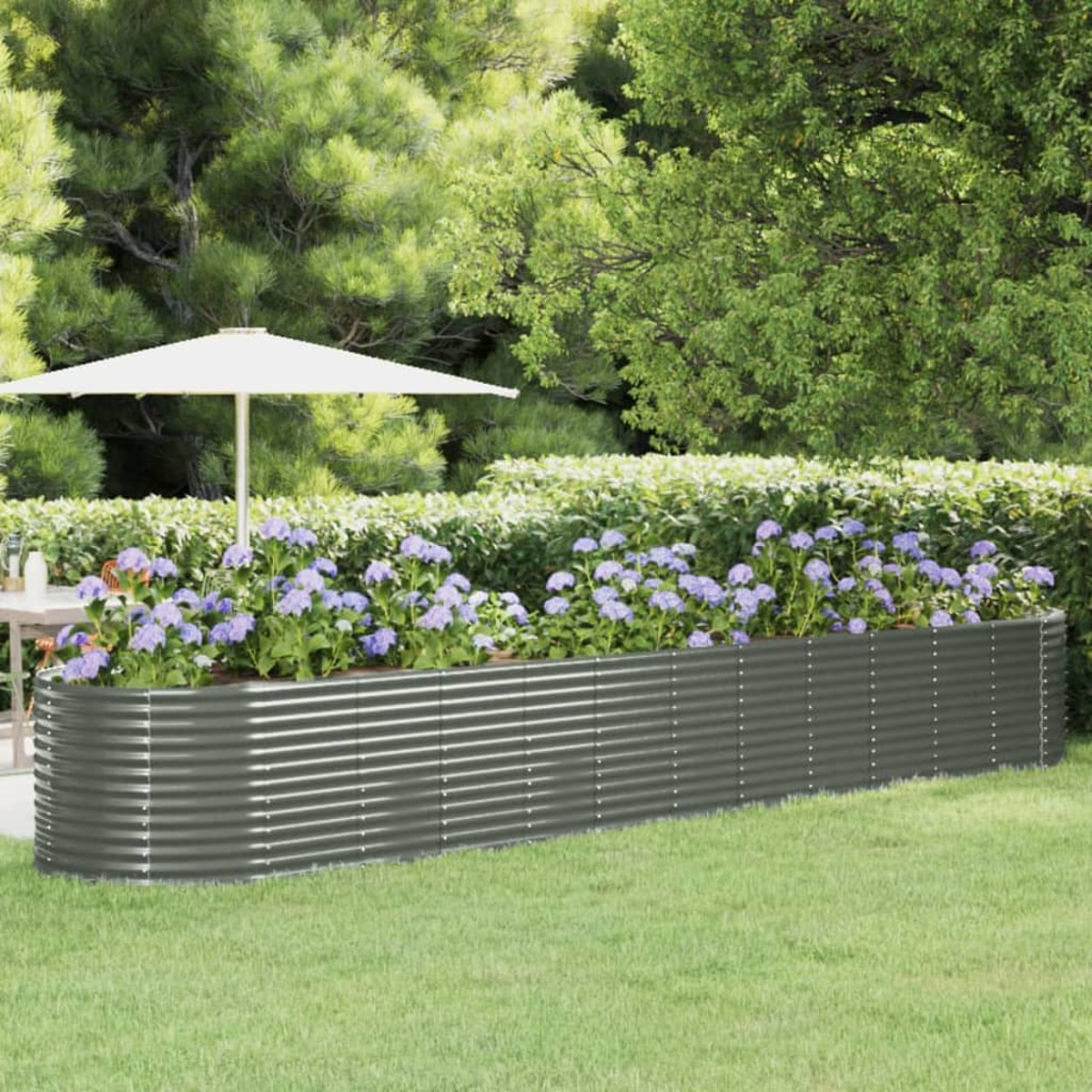 Ein langer, grauer Metallpflanzer mit lila Blumen in einem Garten.