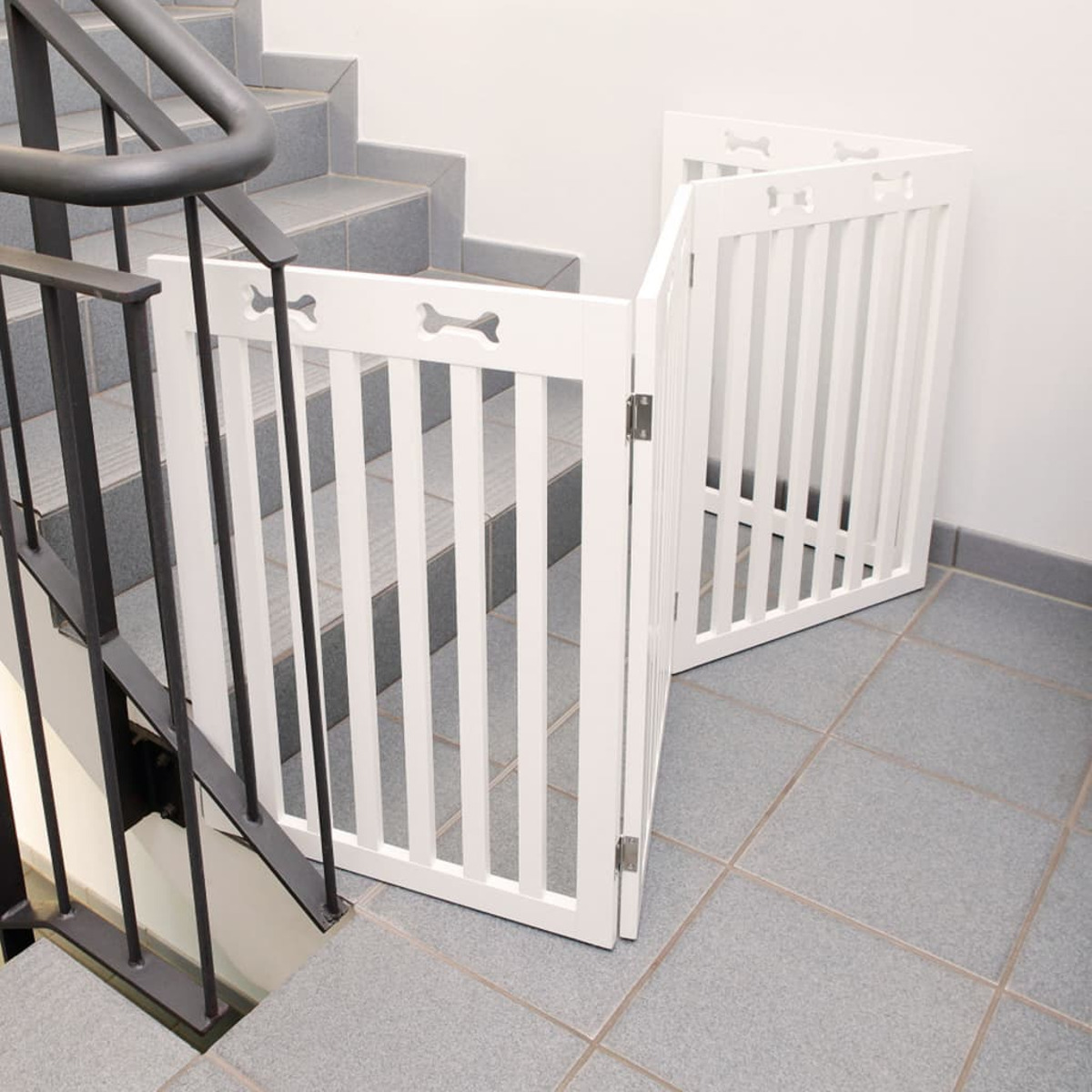 Weißes Haustiergitter, angewinkelt, auf Treppen installiert, mit Knochenaussparungen.