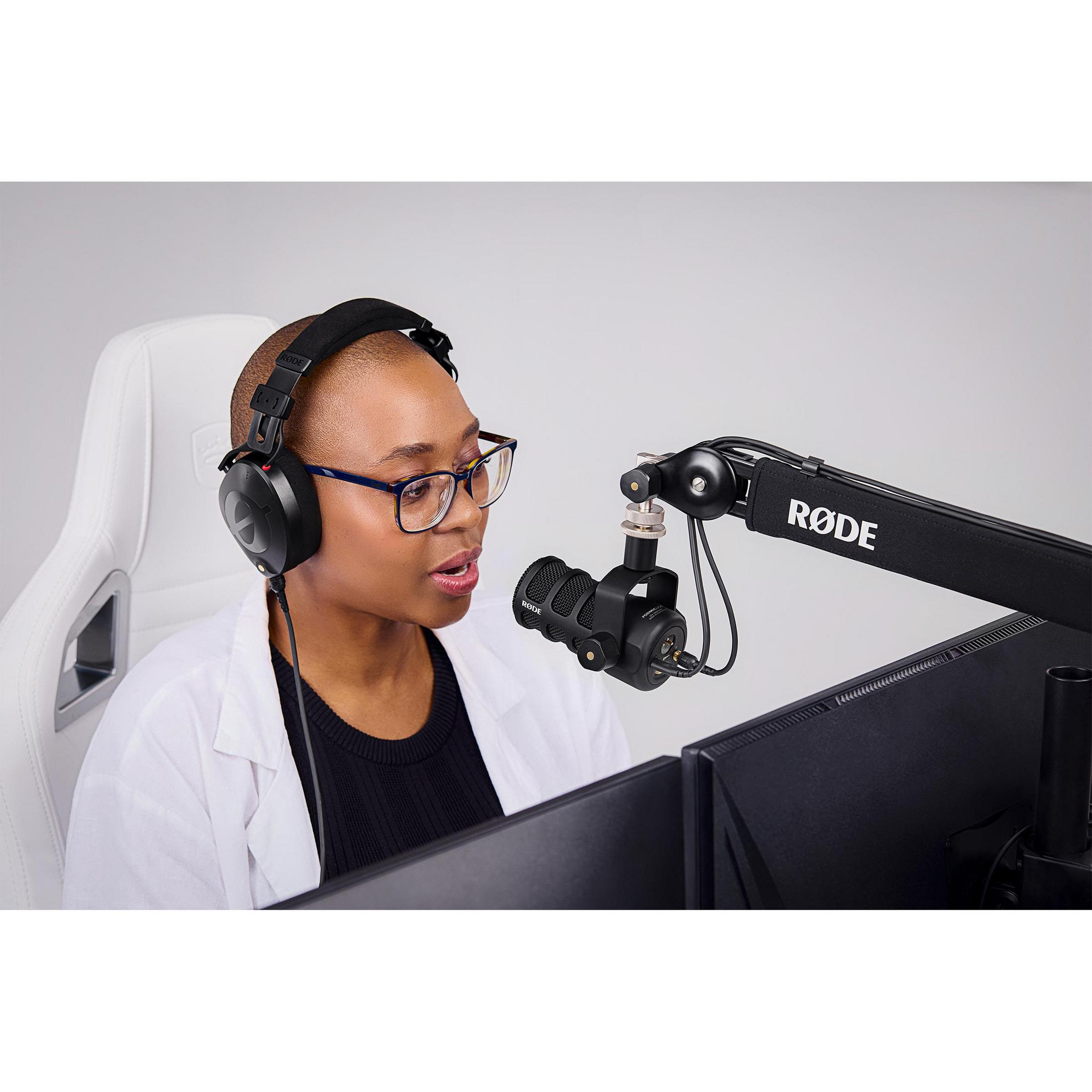 Eine Frau mit Brille und Kopfhörern, die ein Mikrofon zum Aufnehmen und einen Computerbildschirm verwendet.