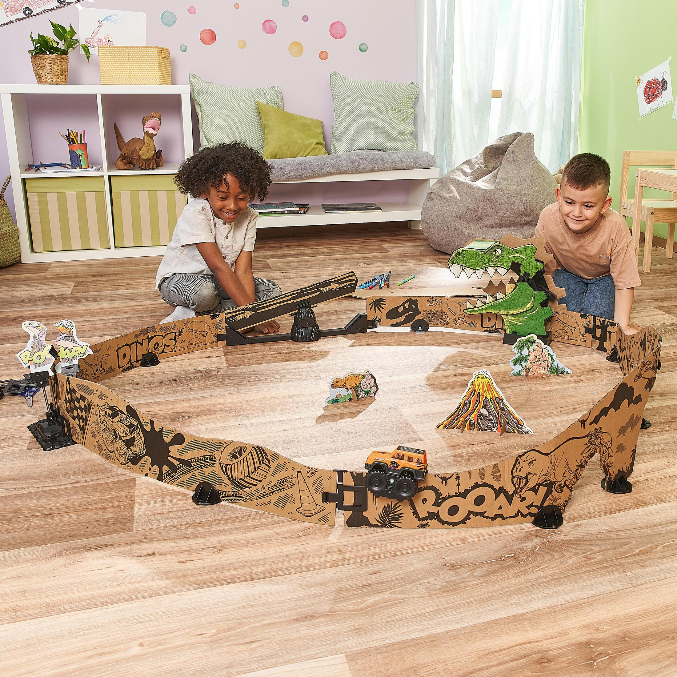 Zwei Kinder spielen mit einer Dinosaurier-Rennstrecke aus Pappe und Spielzeug-Dinosauriern.