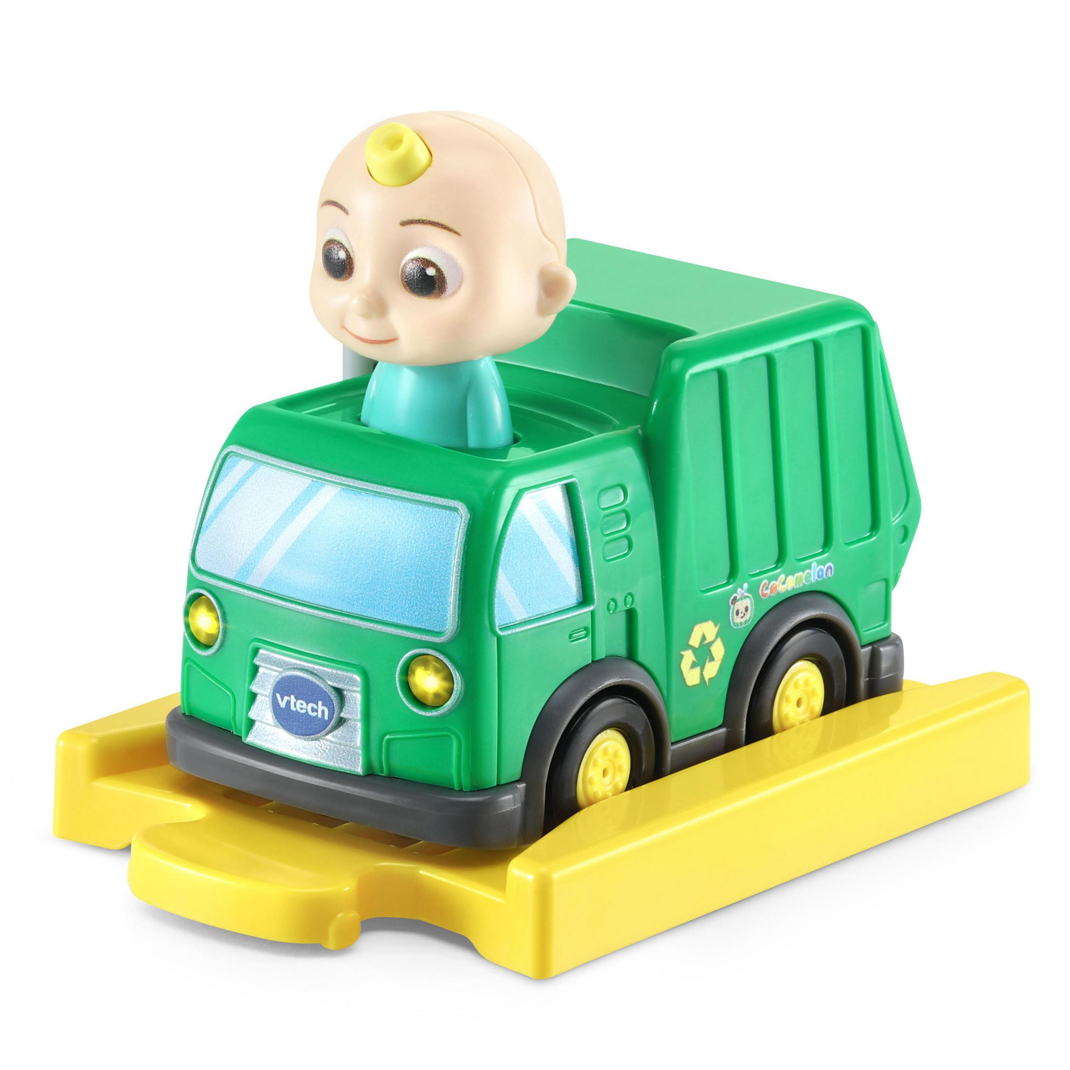 Ein grünes Spielzeug-Müllauto mit einer Person darin wird gezeigt. Der Truck steht auf einer gelben Plattform.