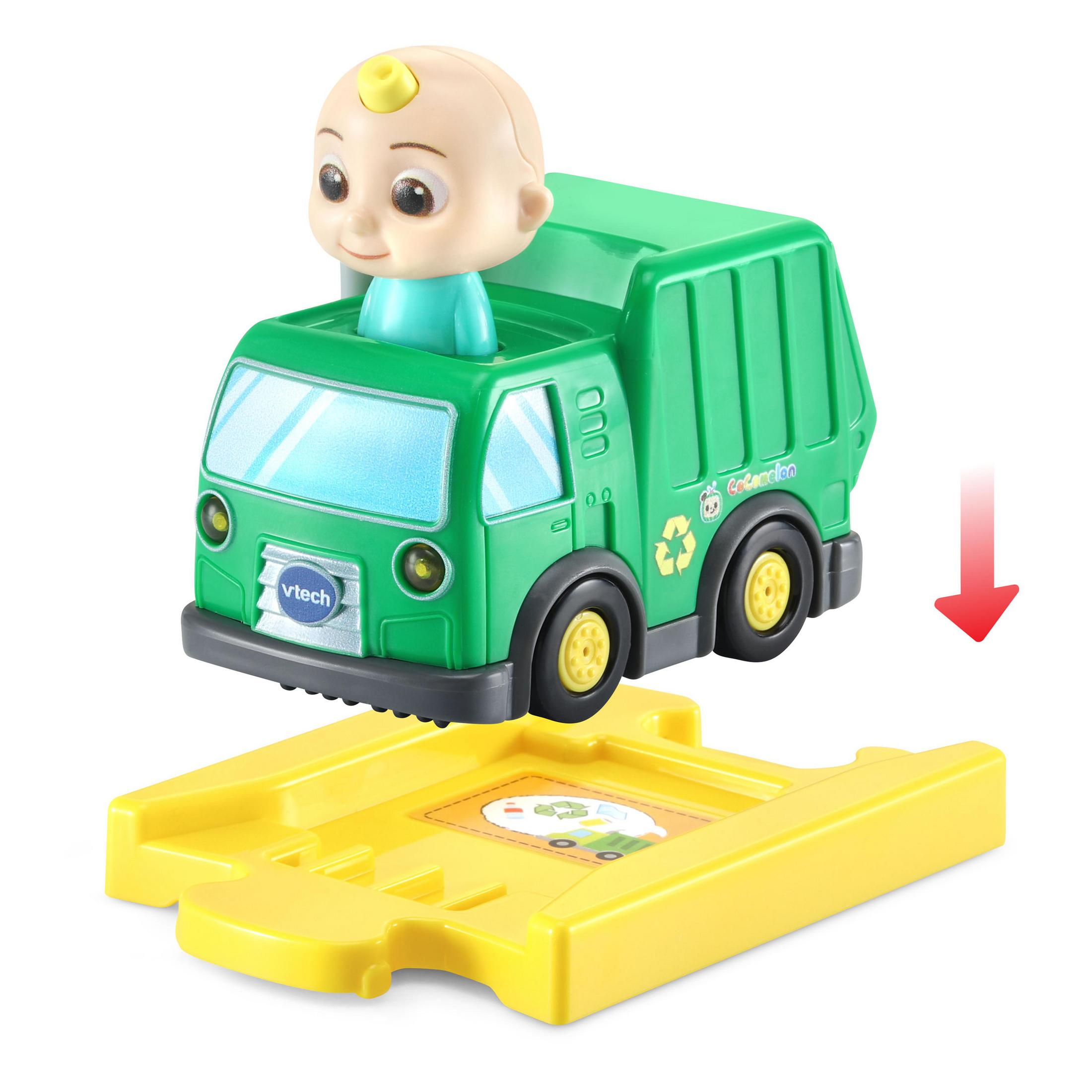 Grüner Spielzeug-Müllwagen mit Babypuppen-Fahrer auf gelber Strecke mit Pfeil nach unten. Weißer Hintergrund.