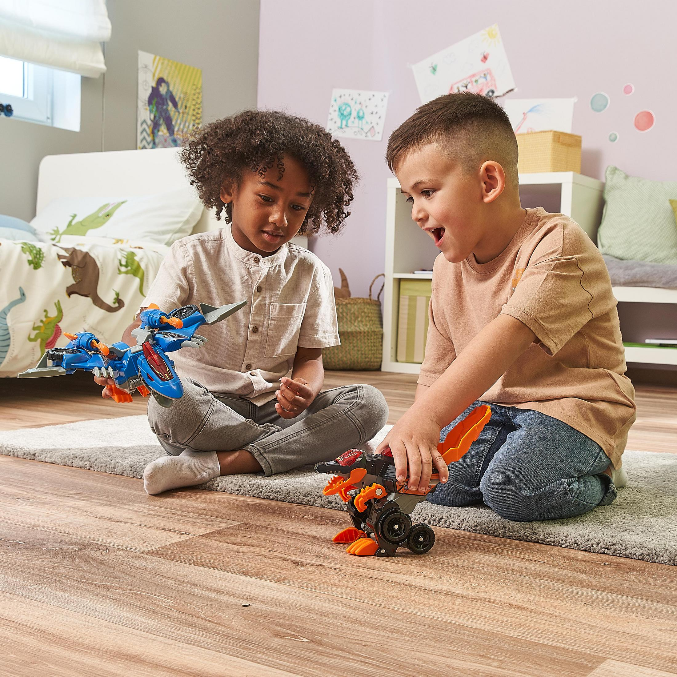 Zwei Kinder spielen mit Spielzeugfahrzeugen auf einem Holzboden in der Nähe eines Teppichs. Im Hintergrund ist ein Schlafzimmer.