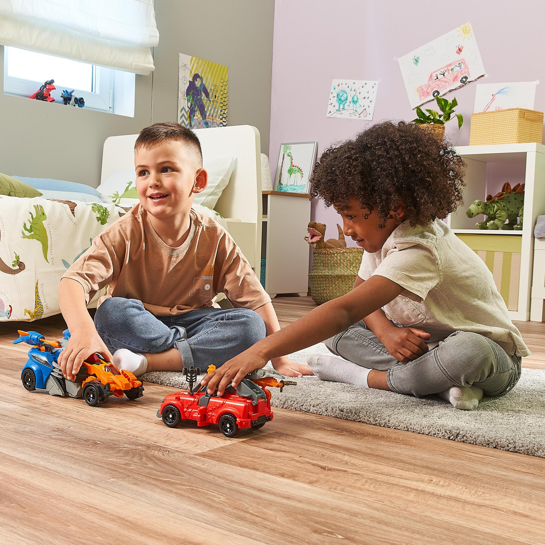 Zwei Kinder spielen mit Spielzeugautos. Die Autos sind blau, orange und rot. Sie sind auf einem Teppich.
