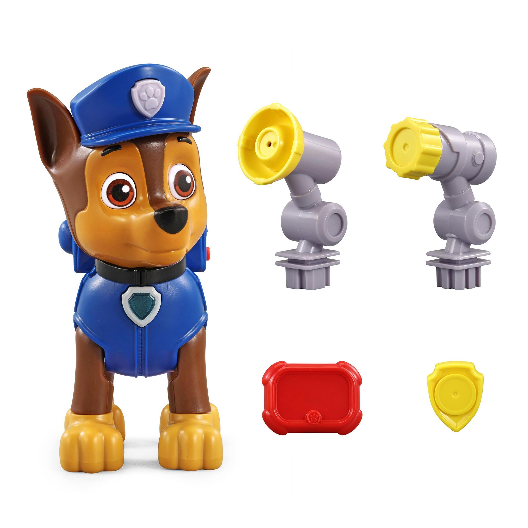 Chase, das Paw Patrol-Spielzeug. Er trägt eine blaue Polizeiuniform. Es gibt Spielzeugzubehör um ihn herum.