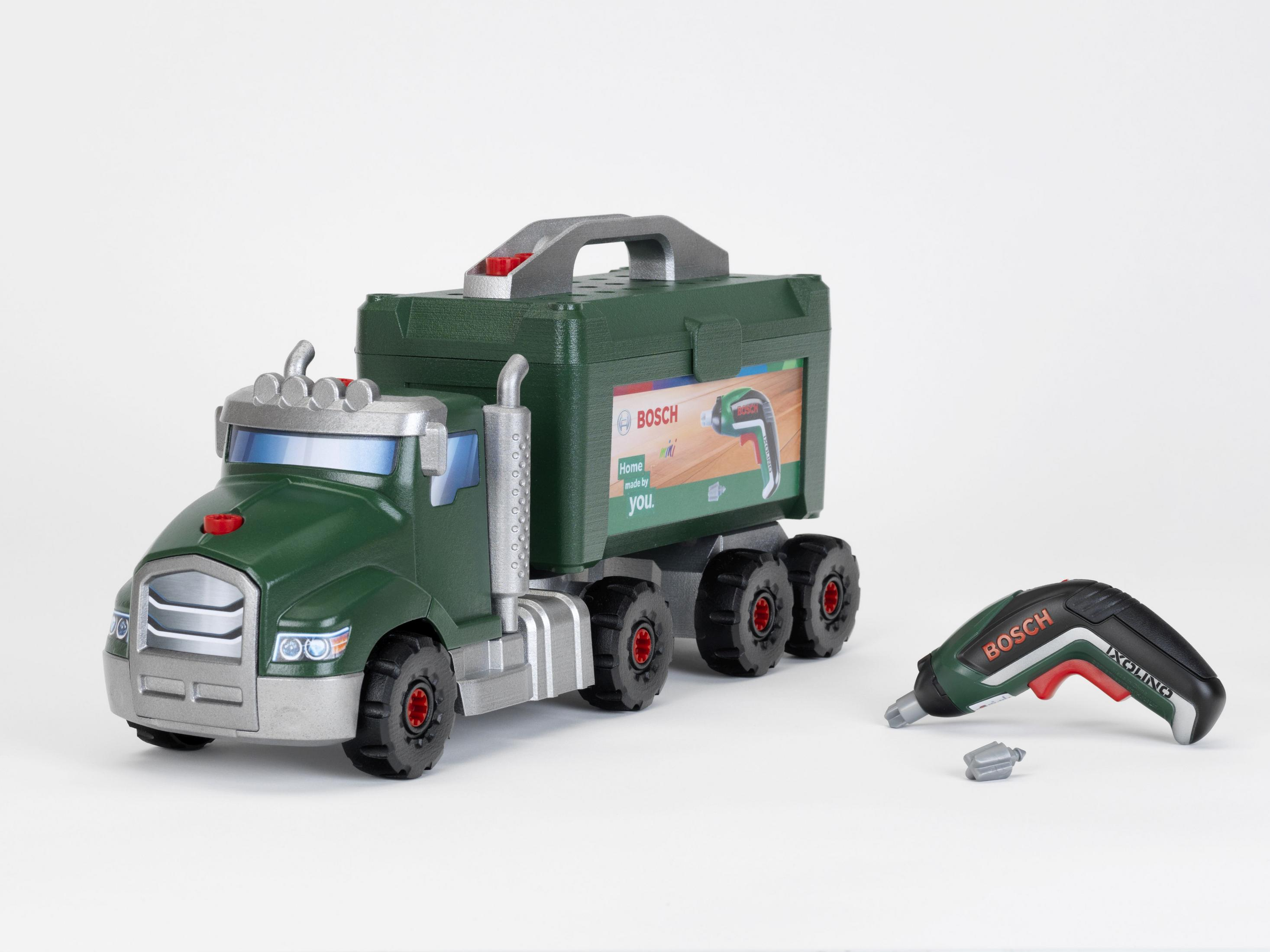 Grüner Spielzeug-LKW mit Werkzeugkasten. Daneben ein kleiner Bohrer. Die Marke ist Bosch.