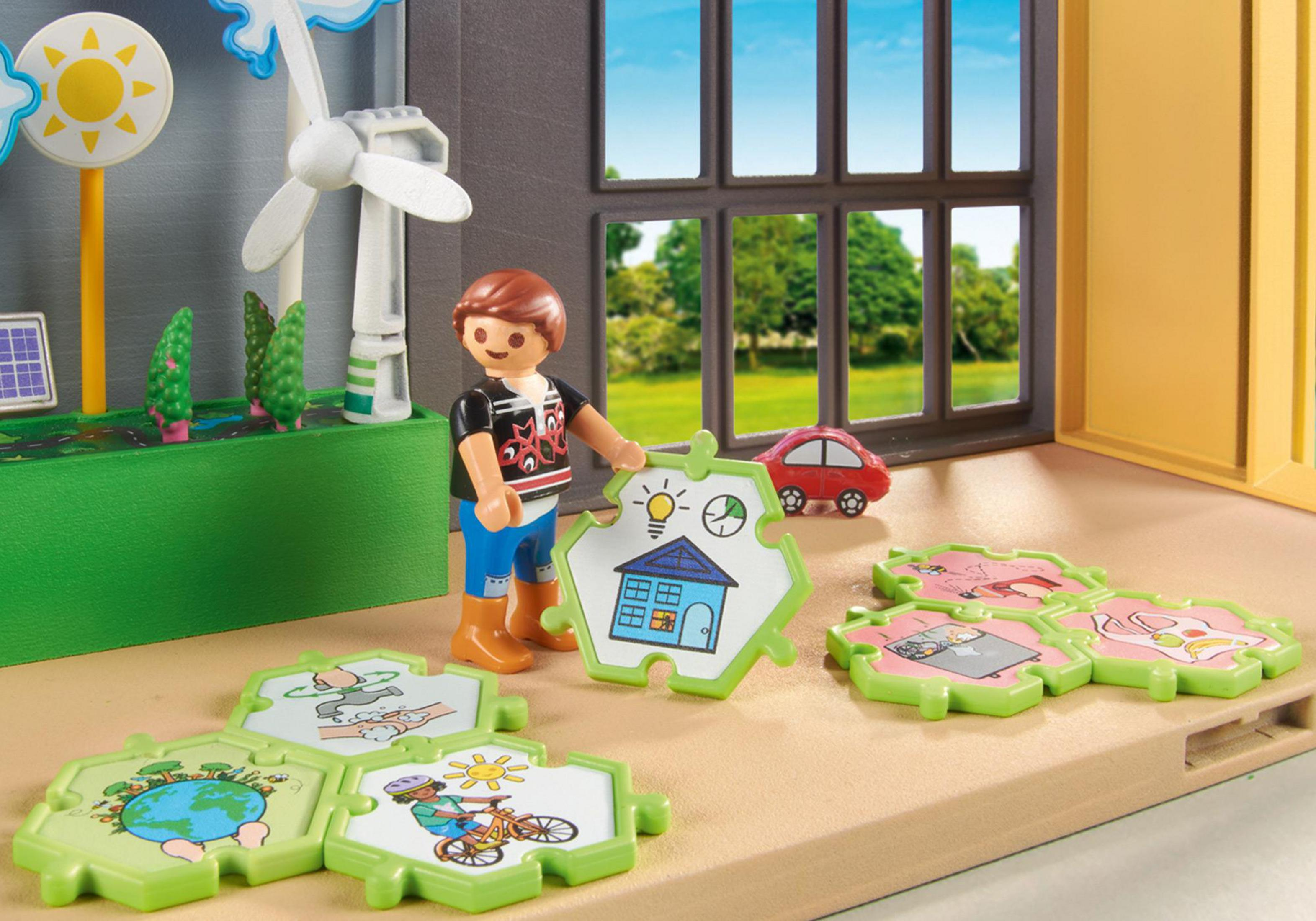 A child with a toy set depicting renewable energy. The scene includes a wind turbine and solar panels.