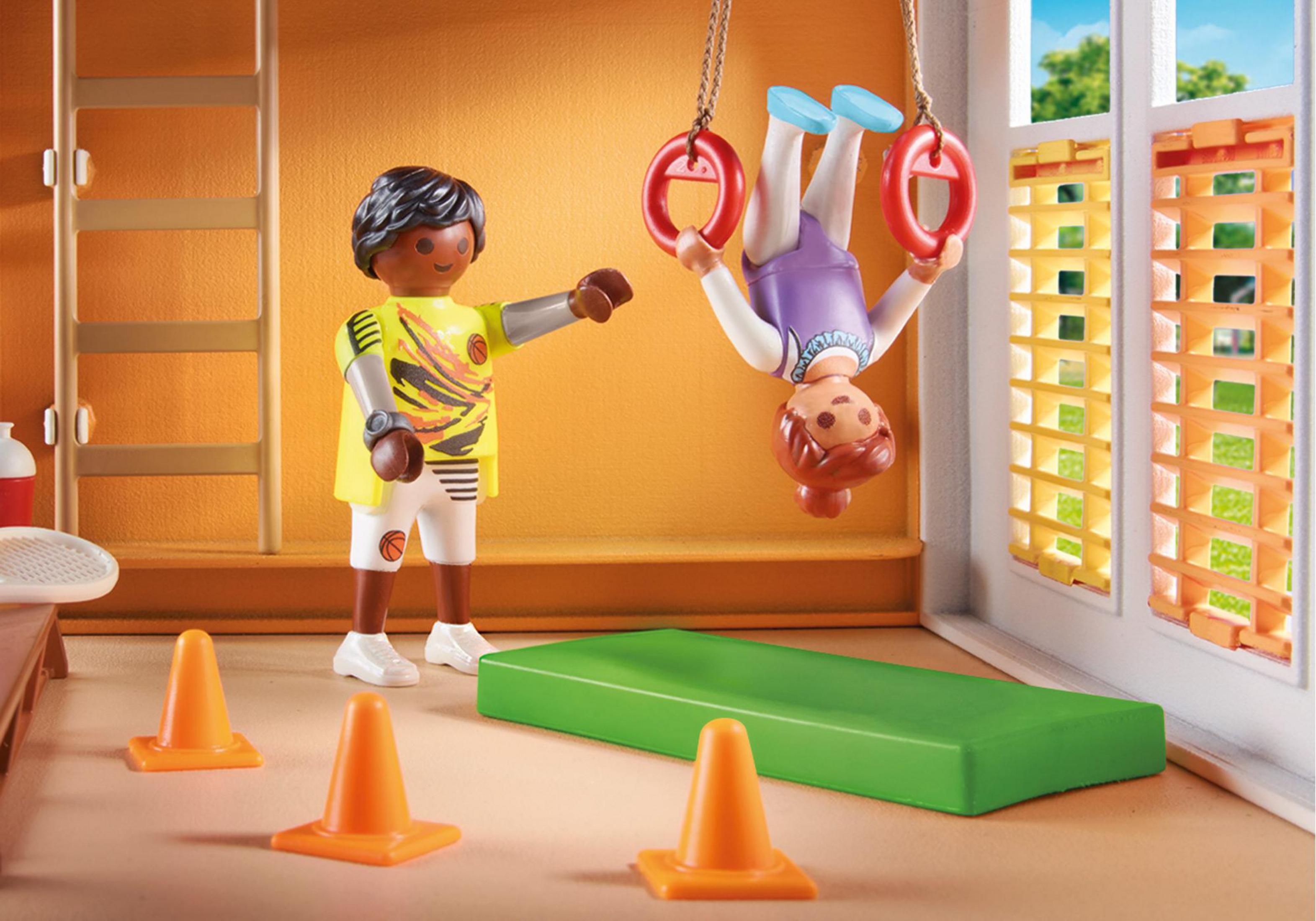 Zwei Kinder spielen in einer Turnhalle mit Trampolin und Gymnastikringen.