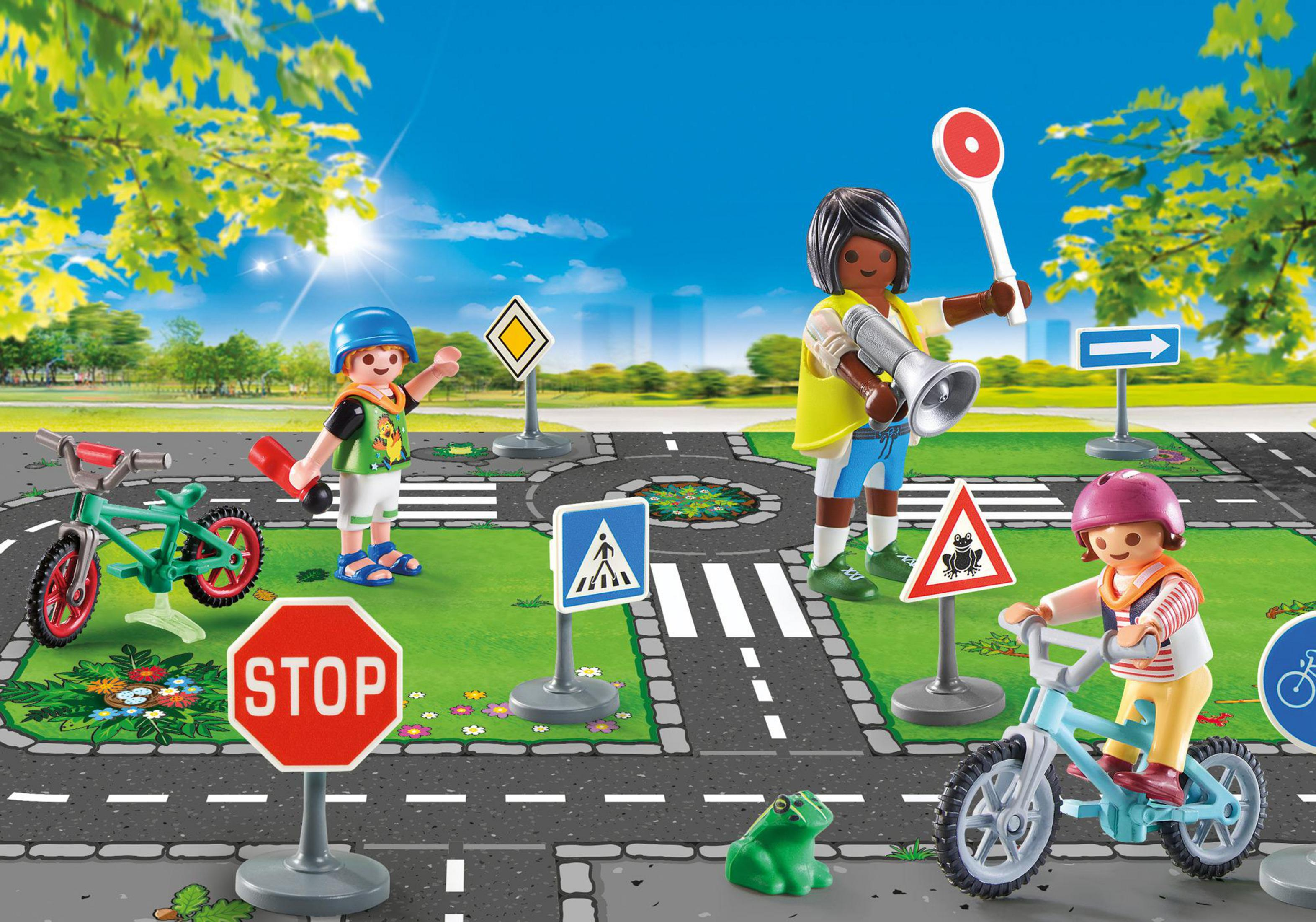 Kinder spielen mit Verkehrsschildern und Fahrrädern auf einer Straße mit einem grünen Frosch.