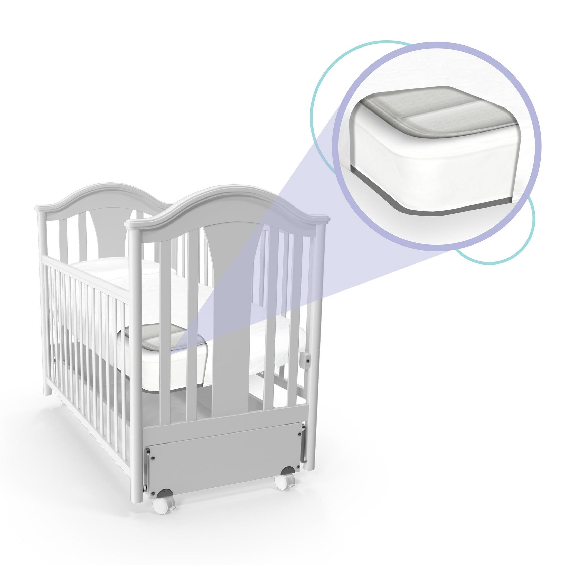Weißes Babybett mit Nahaufnahme einer weißen, grau bedeckten Matratze.