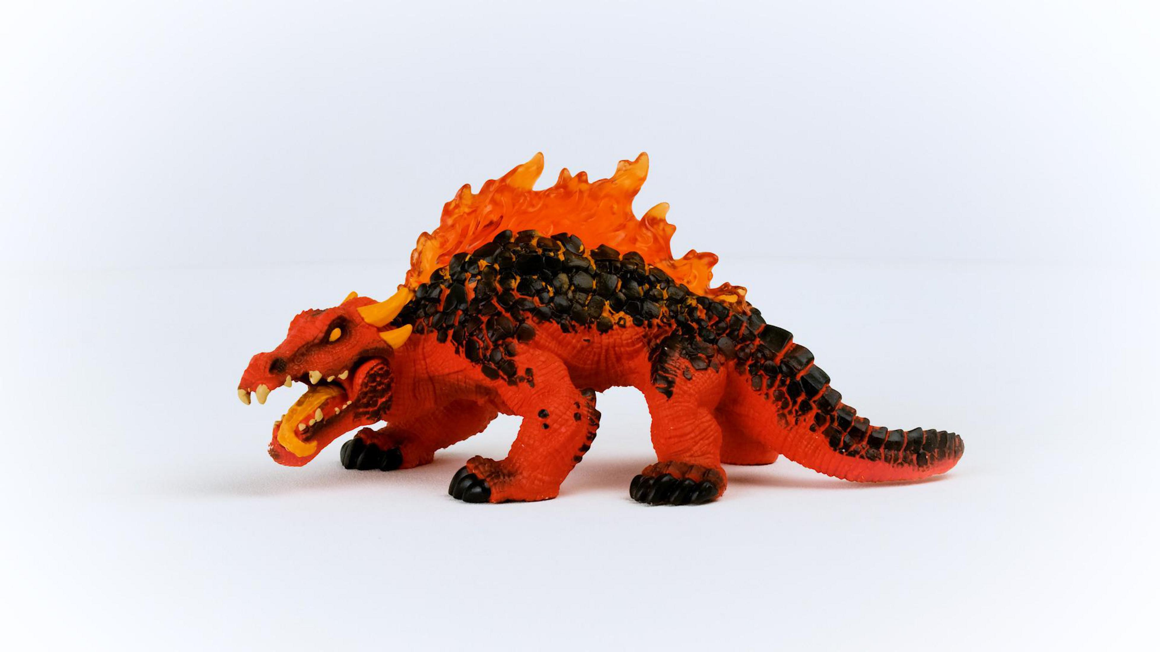 Figurina di drago giocattolo con colori rossi e arancioni. Ha fiamme sulla schiena e bocca aperta.