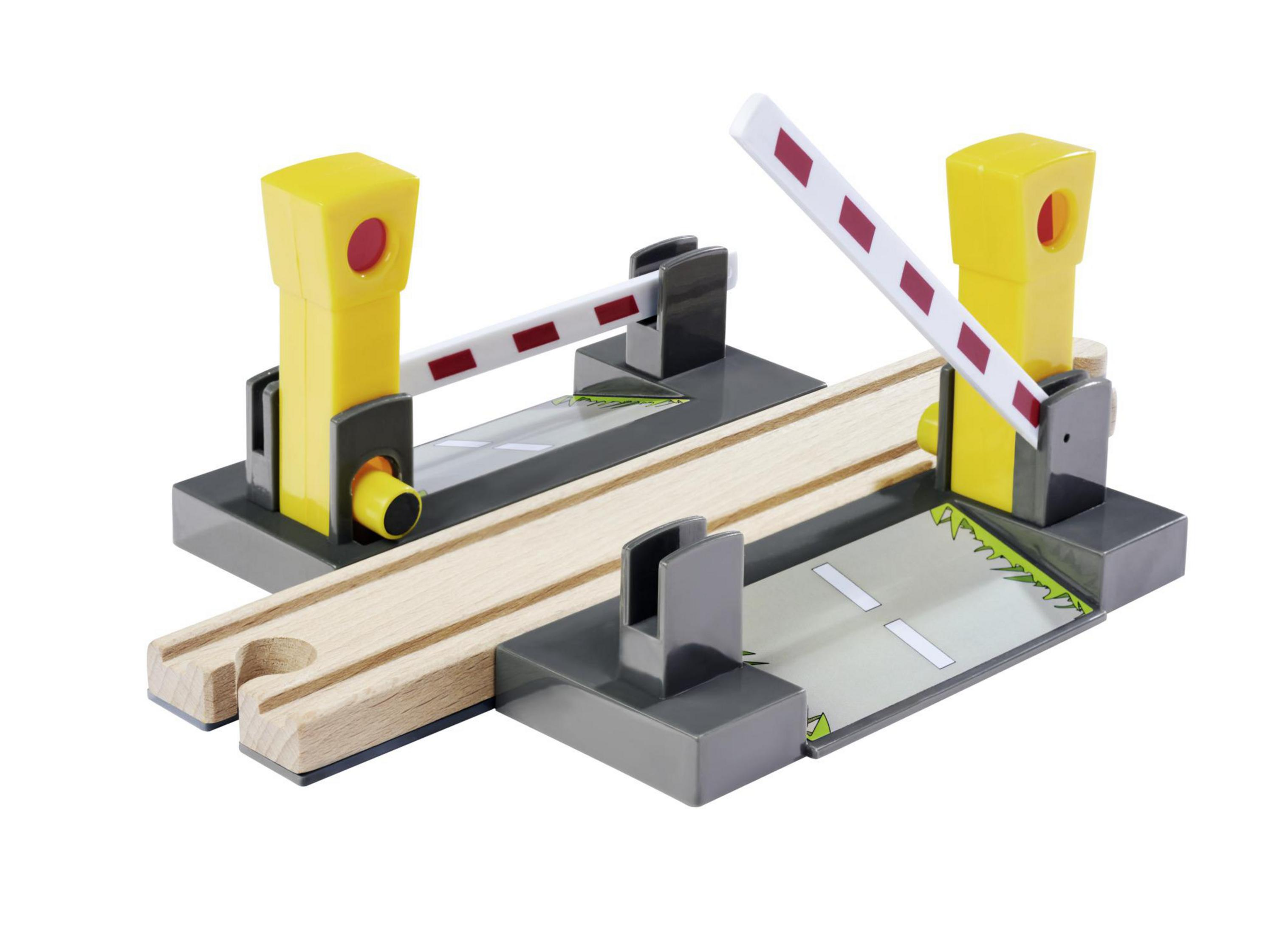 Ein Spielzeug-Bahnübergang mit gelben Lichtern und weiß-roten Schranken.