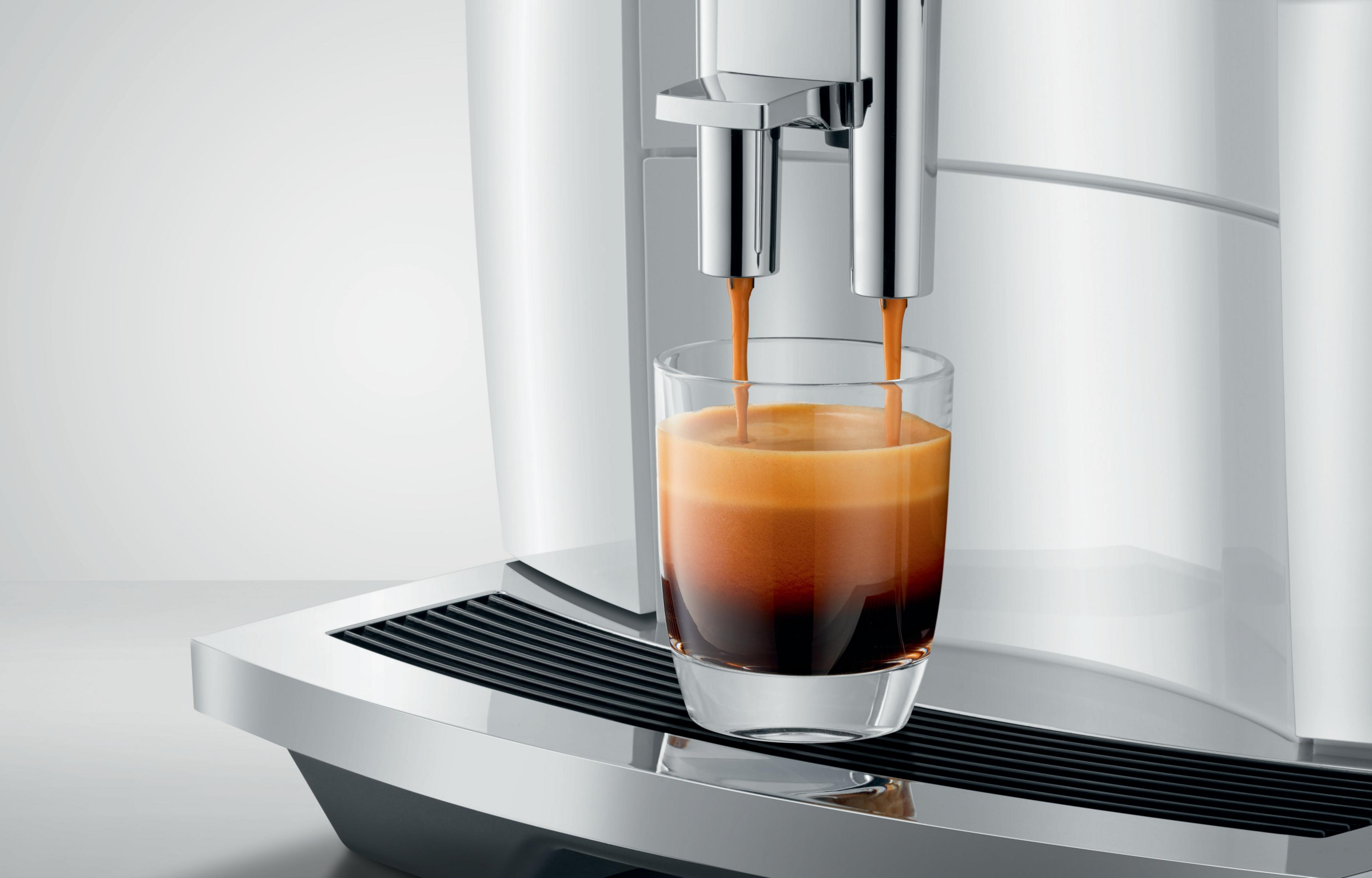 Eine Espressomaschine, die Kaffee in ein klares Glas abgibt und Kaffeeschichten zeigt.