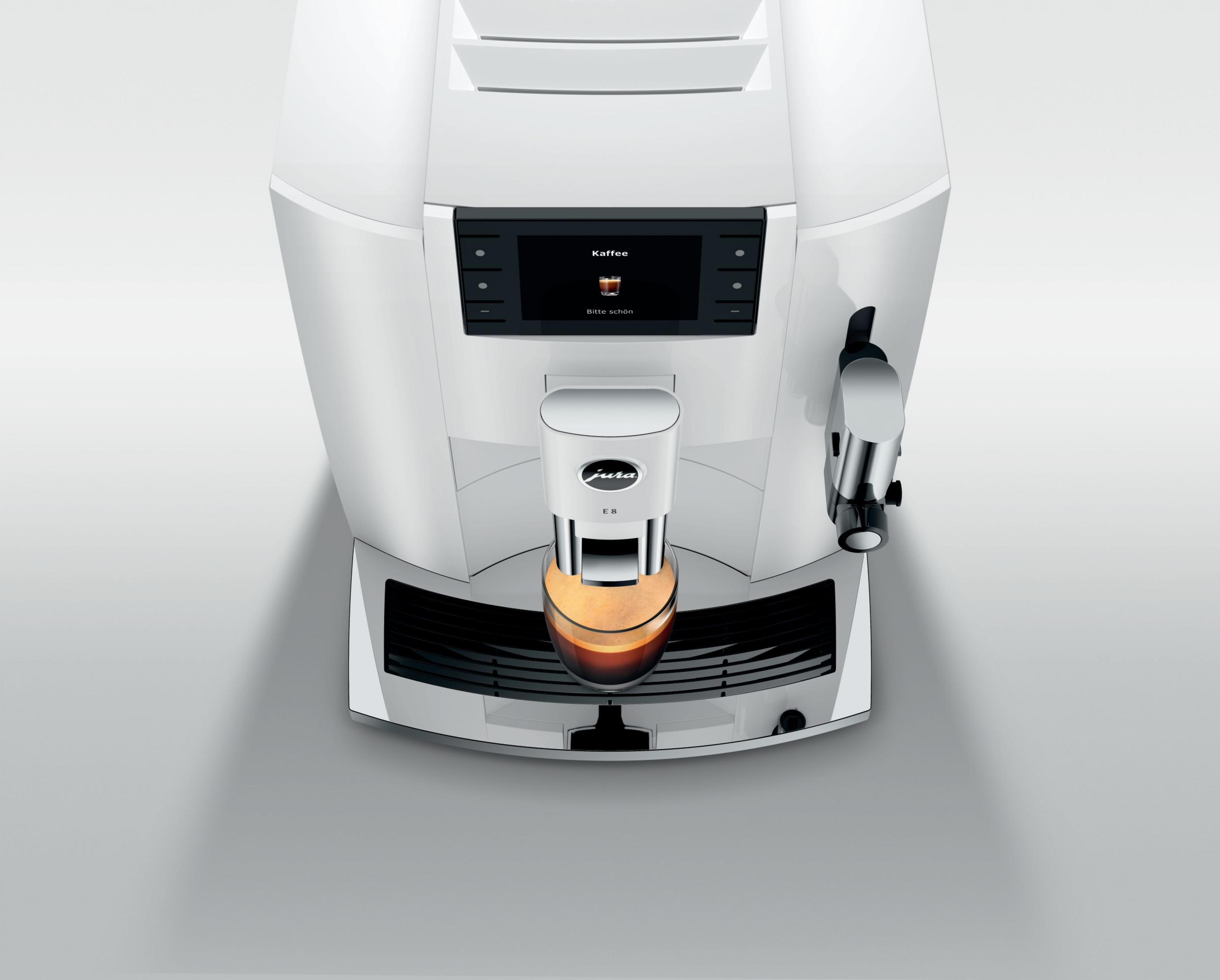 Weiße Kaffeemaschine, die Kaffee ausgibt. Grauer Hintergrund.