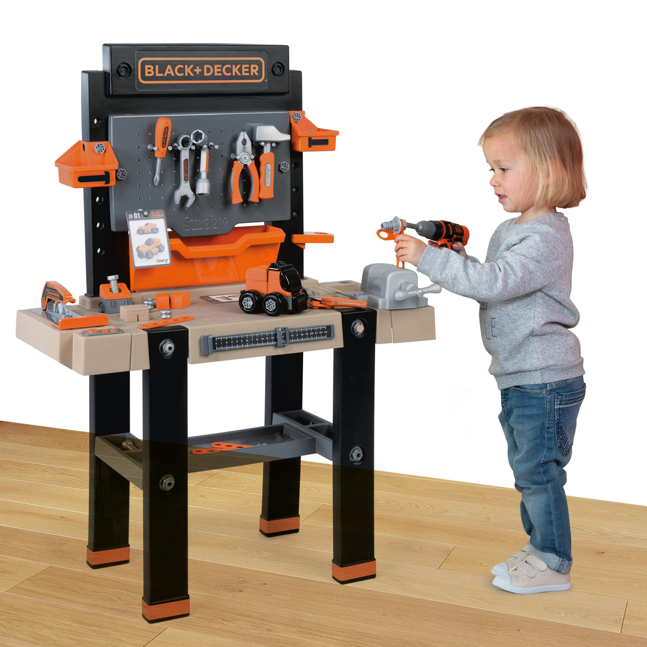 Ein Kind spielt mit einer Black+Decker Werkbank. Werkzeuge hängen an der Tafel.